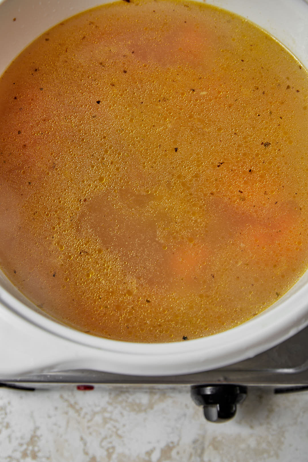 vegetable broth added to a large white saucepan.
