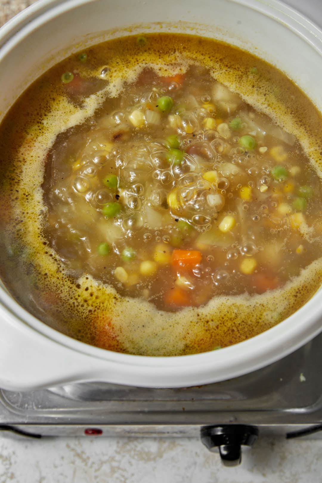 vegetables simmering in vegetable broth in a large white pot.