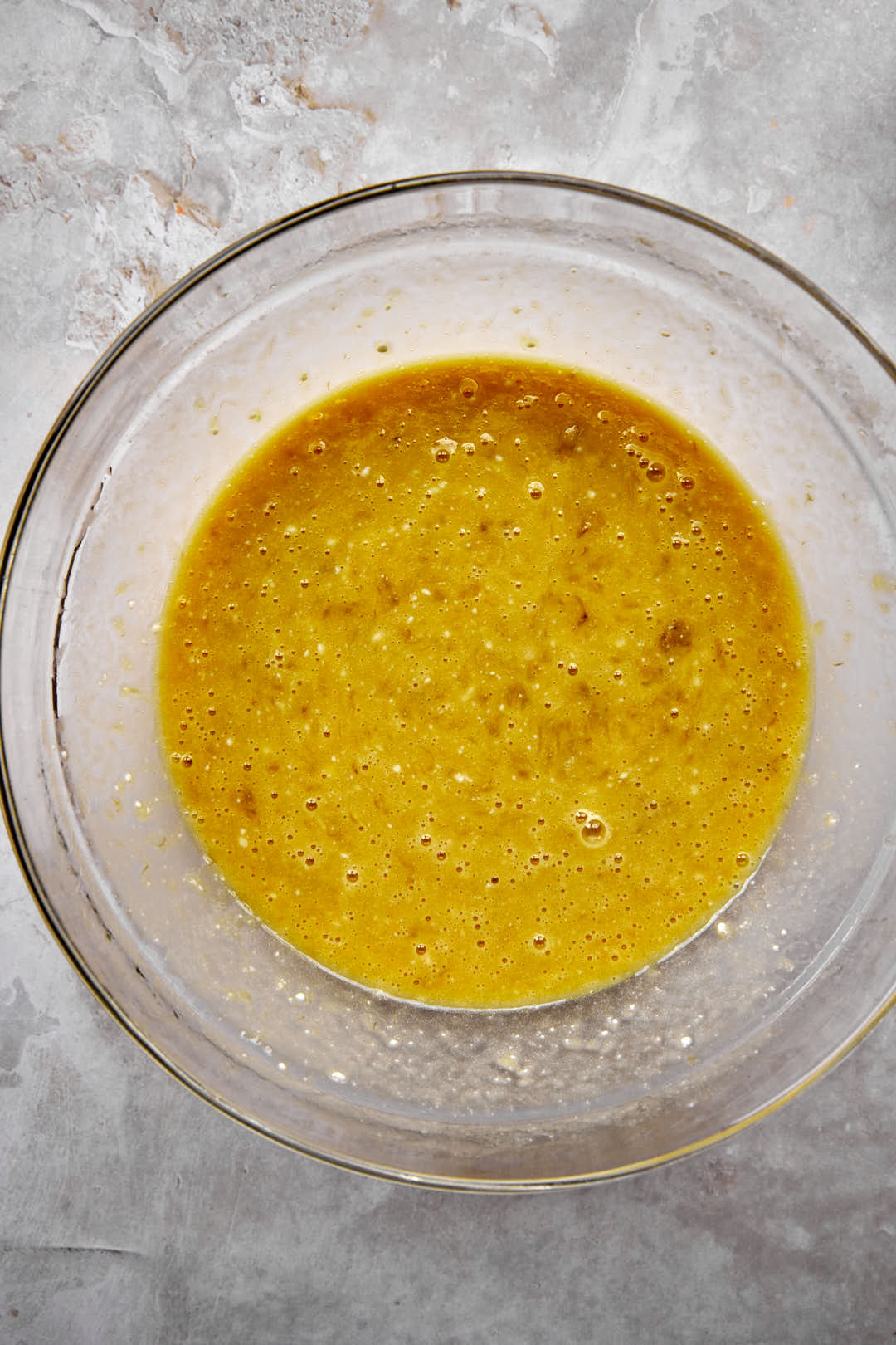 wet ingredients for banana bread mixed together in a glass bowl.