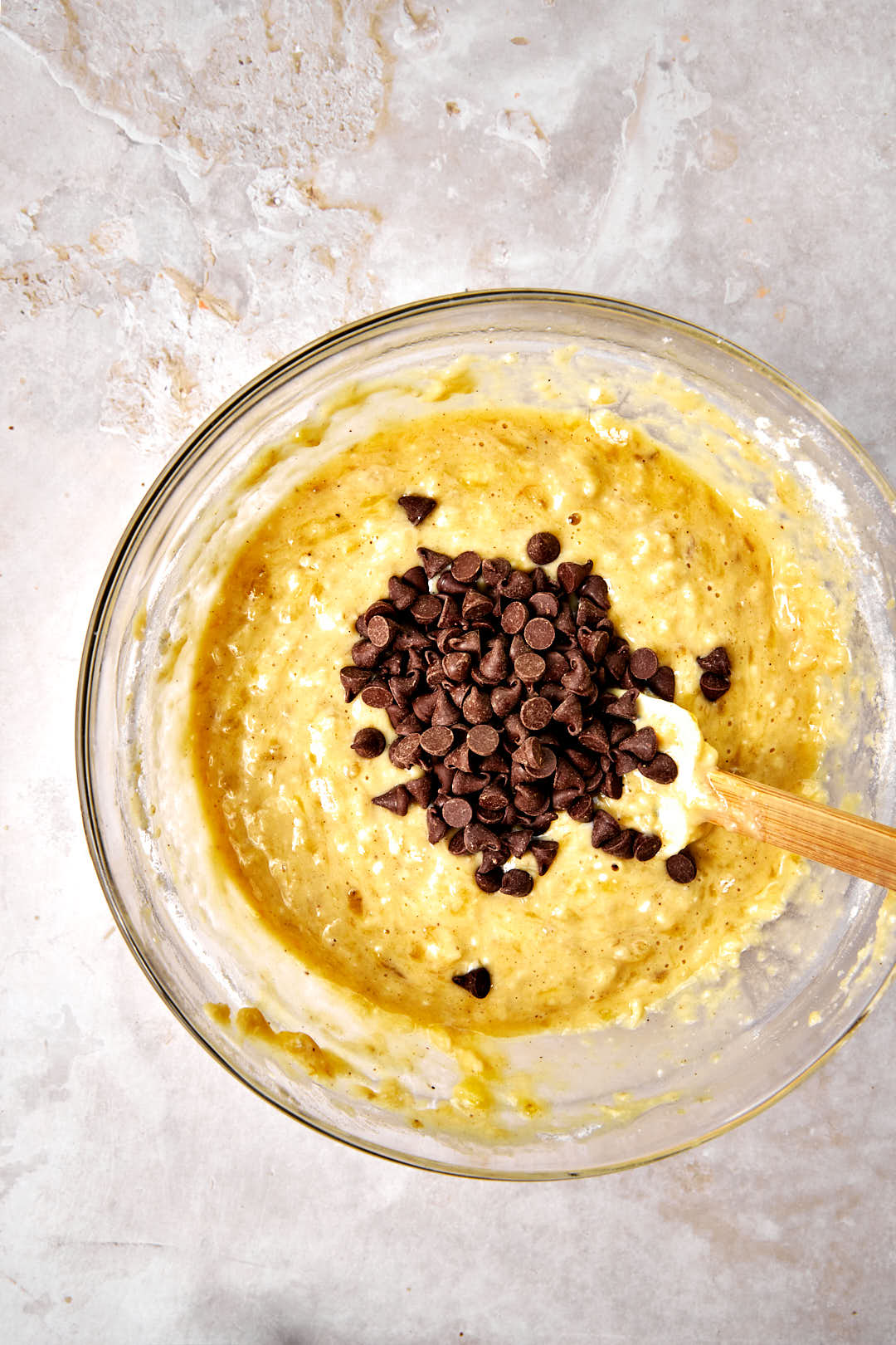 chocolate chips added to banana bread batter in a glass bowl.