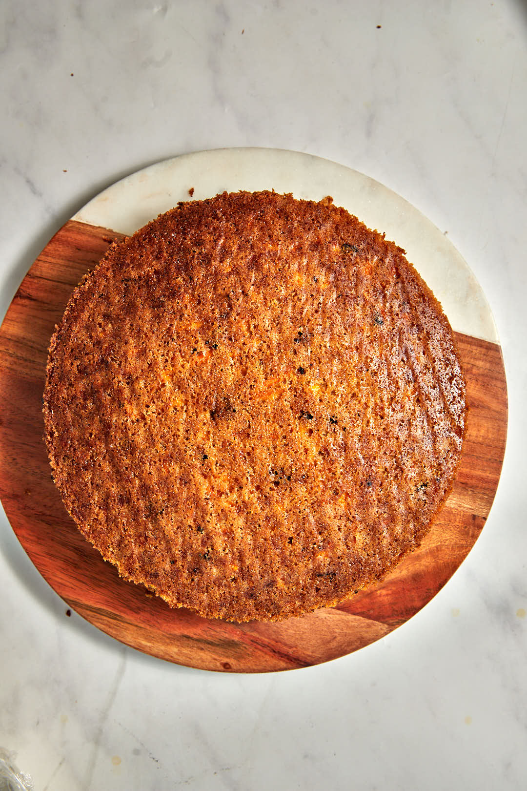one layer of a carrot cake on a wooden cake plate.