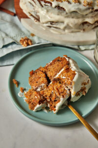 moist carrot cake on a blue plate with forkfuls being taken out.
