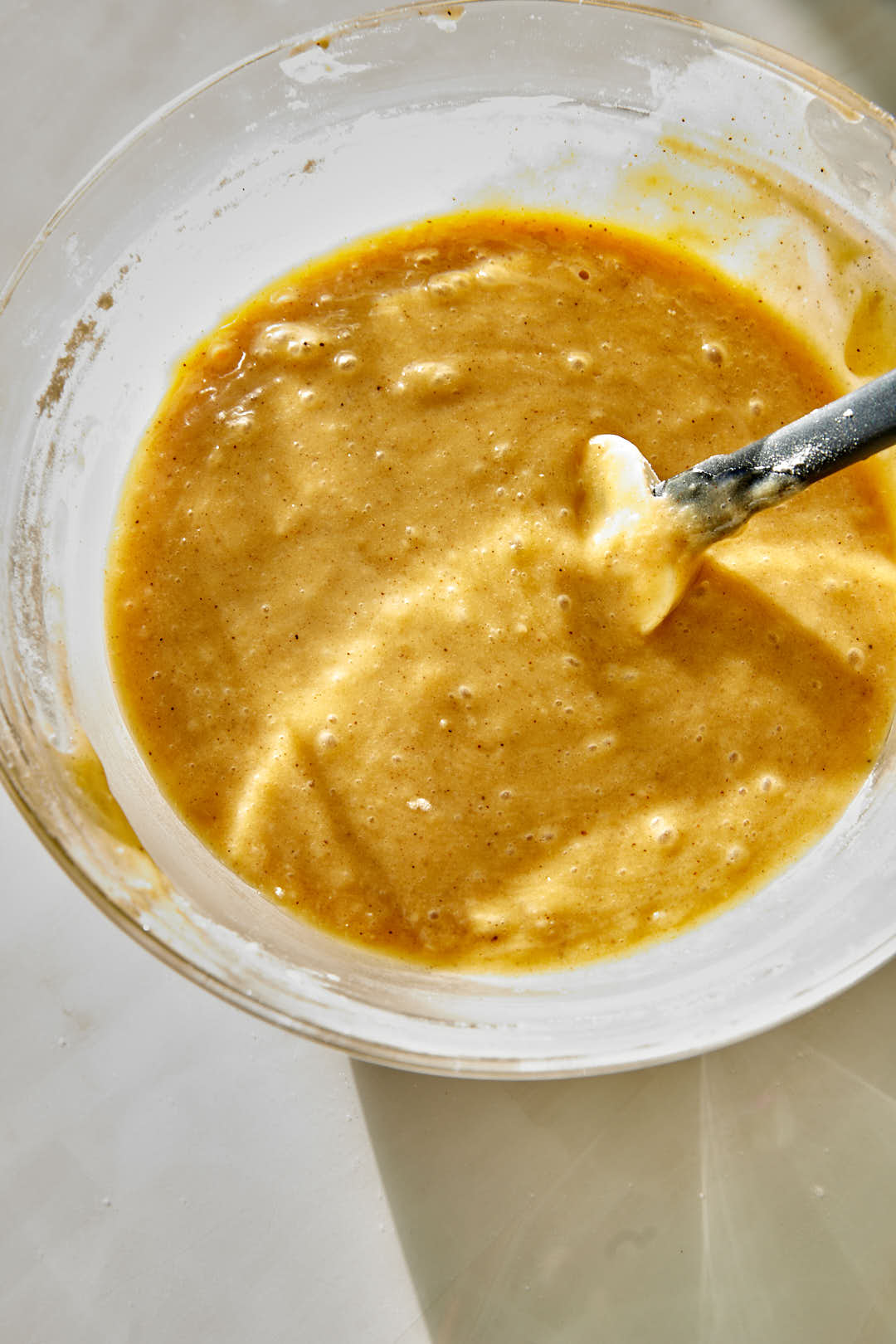 mixed cake batter in glass bowl with a spatula.