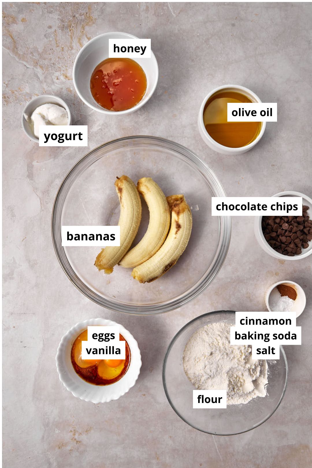ingredients you need to make olive oil banana bread on a plain background.