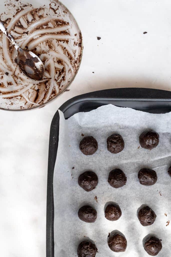 rolled out balls of oreo truffles on a parchment paper lined baking sheet