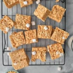 overhead view of peanut butter rice krispie squares on a wire rack with a bowl of Rice Krispies and a spoonful of peanut butter.