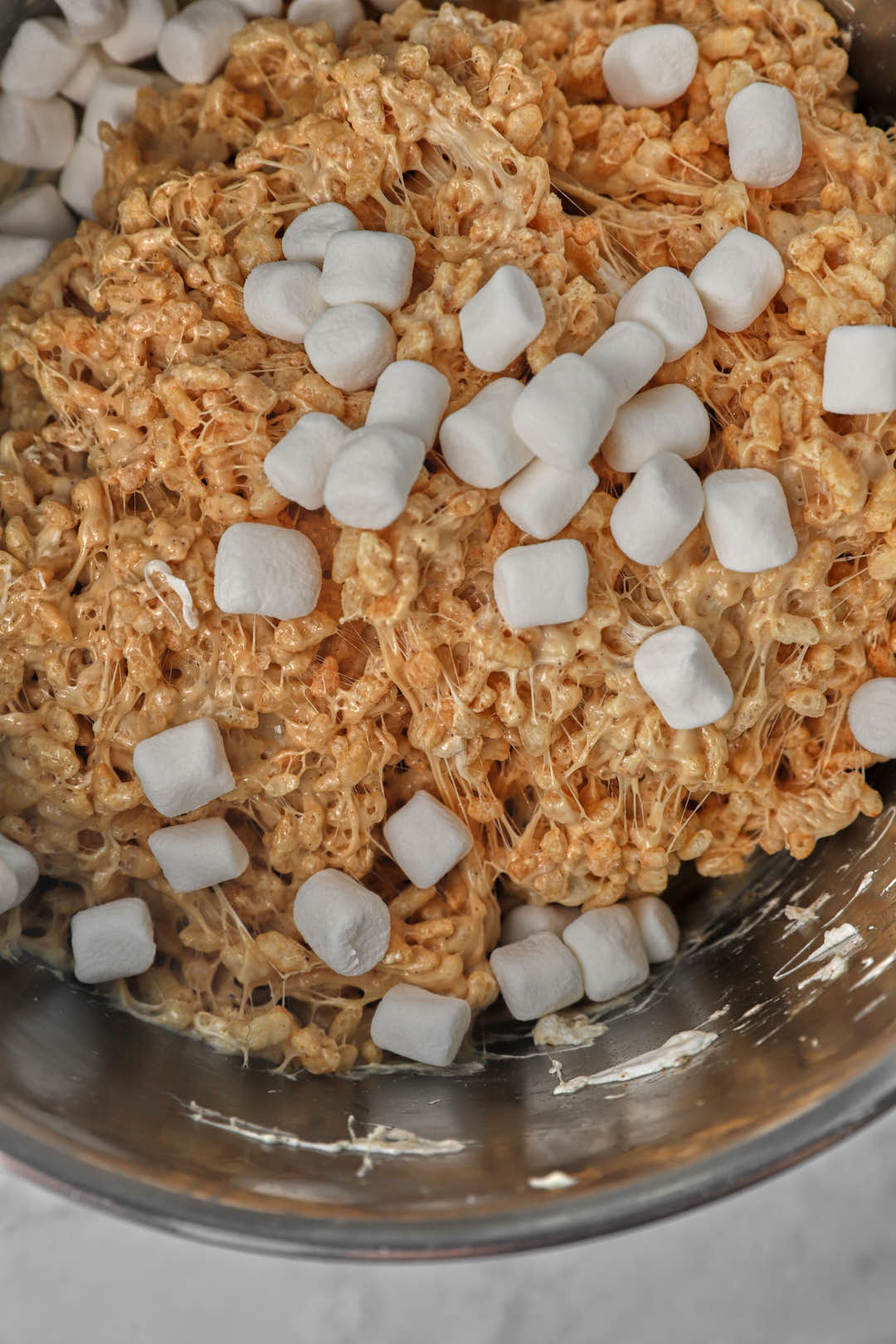 mini marshmallows added on top of the peanut butter rice krispie mixture in a pot.