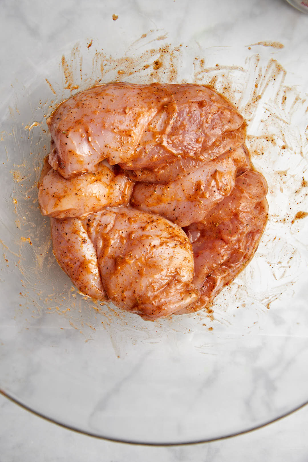 chicken breats marinating in a glass bowl.
