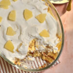large pyrex dish of pineapple trifle on a pink background.