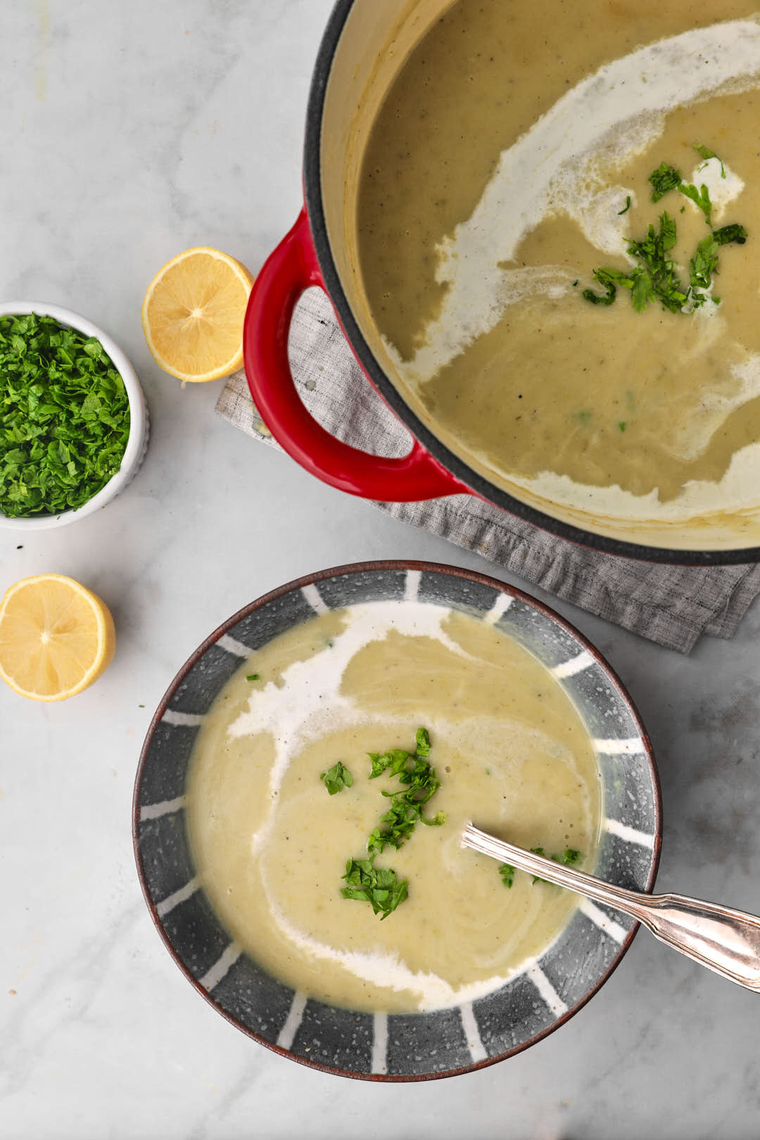 a bowl of zucchini and potato soup with the pot of soup in the background.