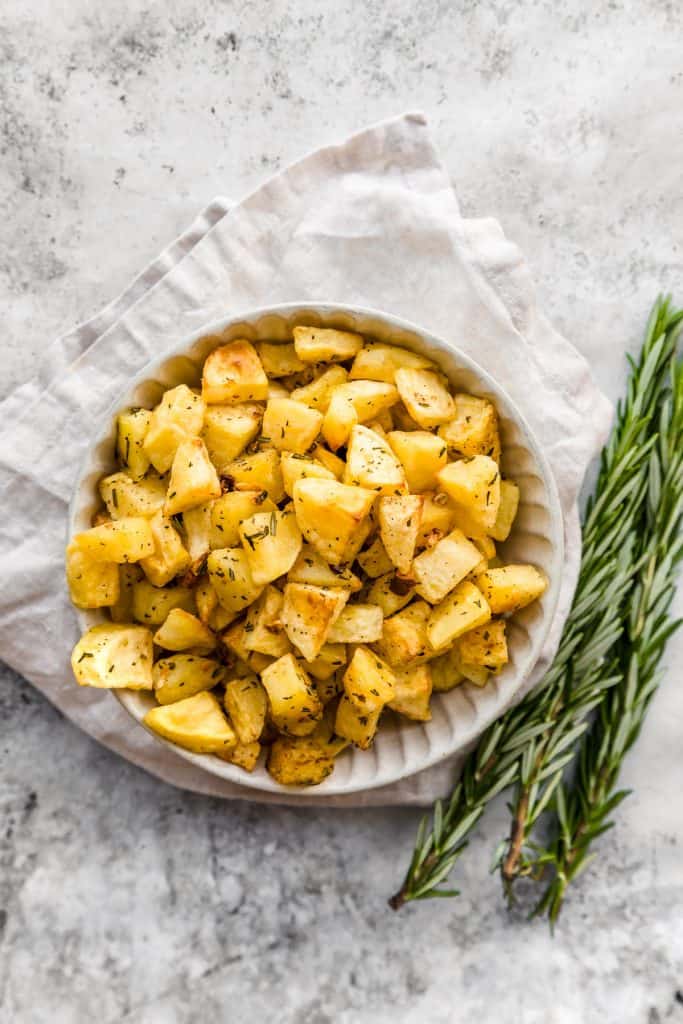 Bowl of roasted potato parmentier with fresh rosemary on the side
