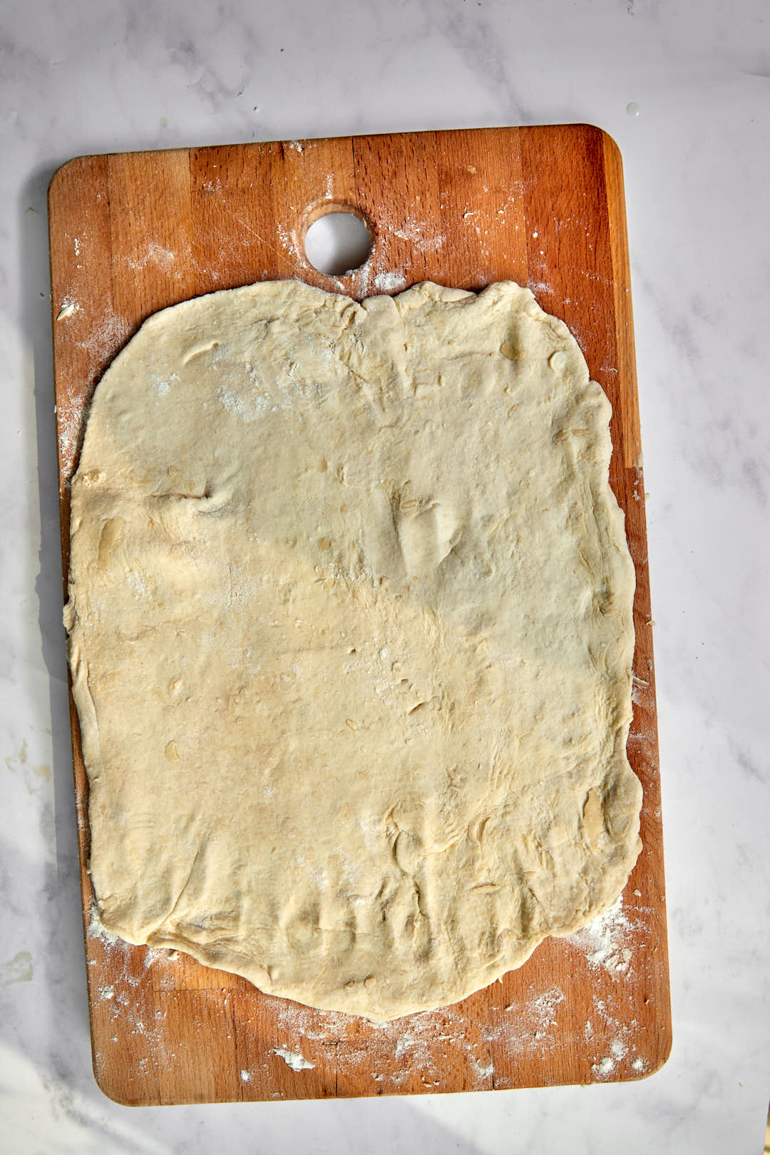 puff pastry dough rolled out into a large rectangle on a wooden cutting board.