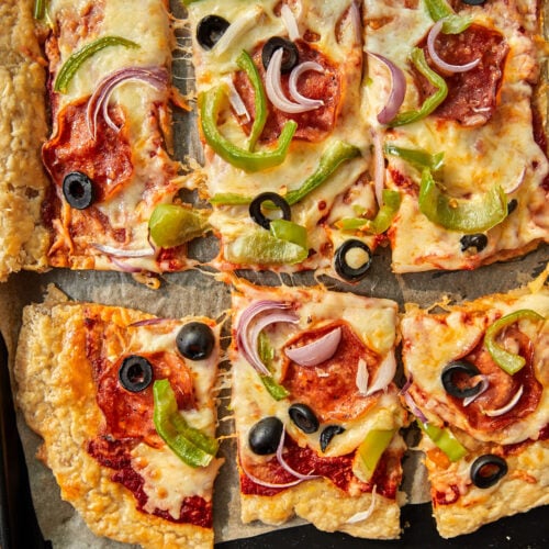 Close up photo of puff pastry pizza squares on a parchment lined baking sheet.