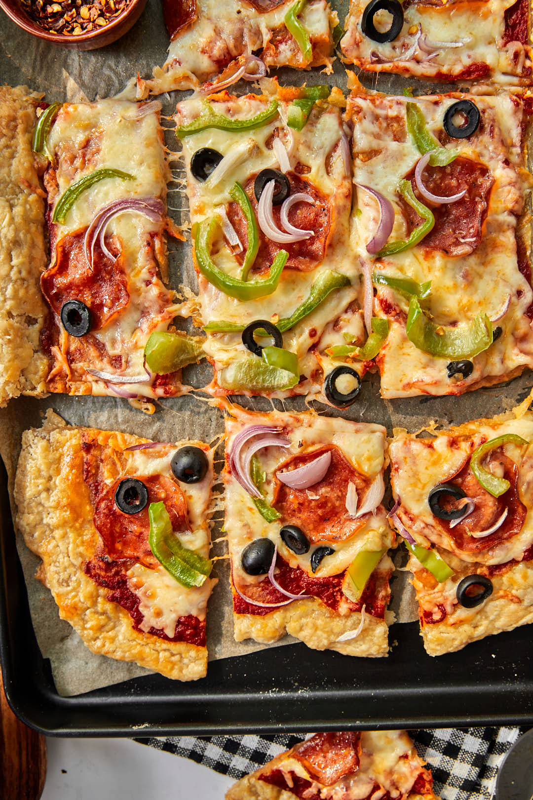 Close up photo of puff pastry pizza squares on a parchment lined baking sheet.