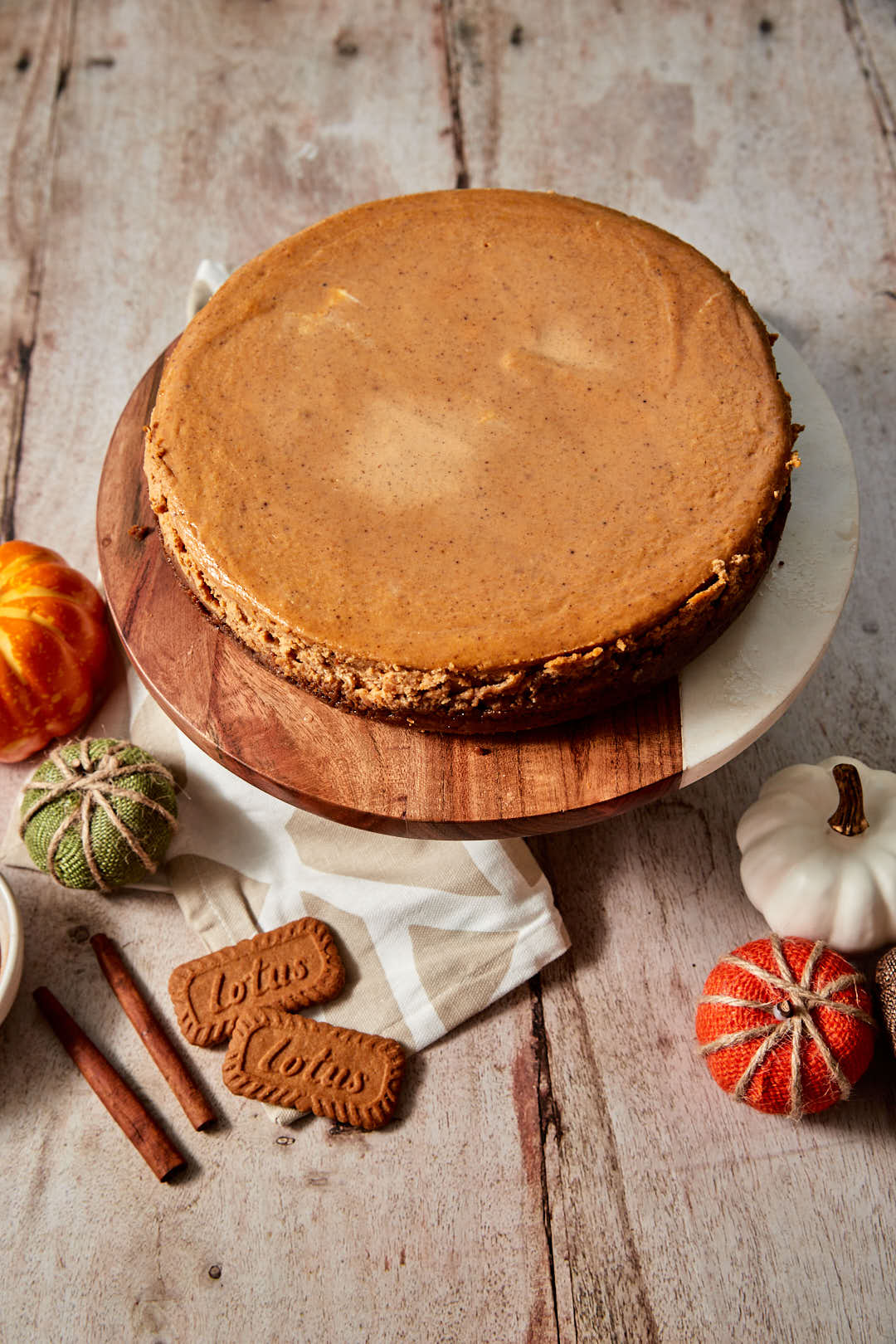 cooled pumpkin cheesecake on marlbe and wood cake stand.