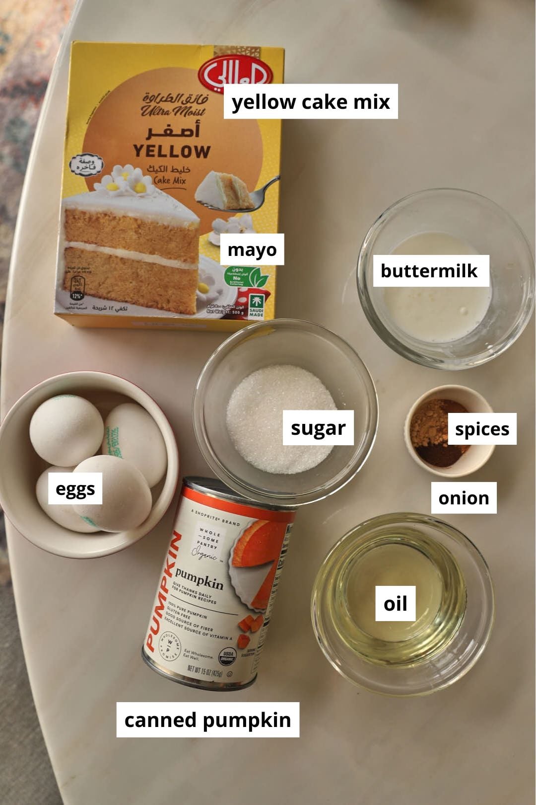 ingredients needed to make pumpkin cake from cake mix on a marble table.