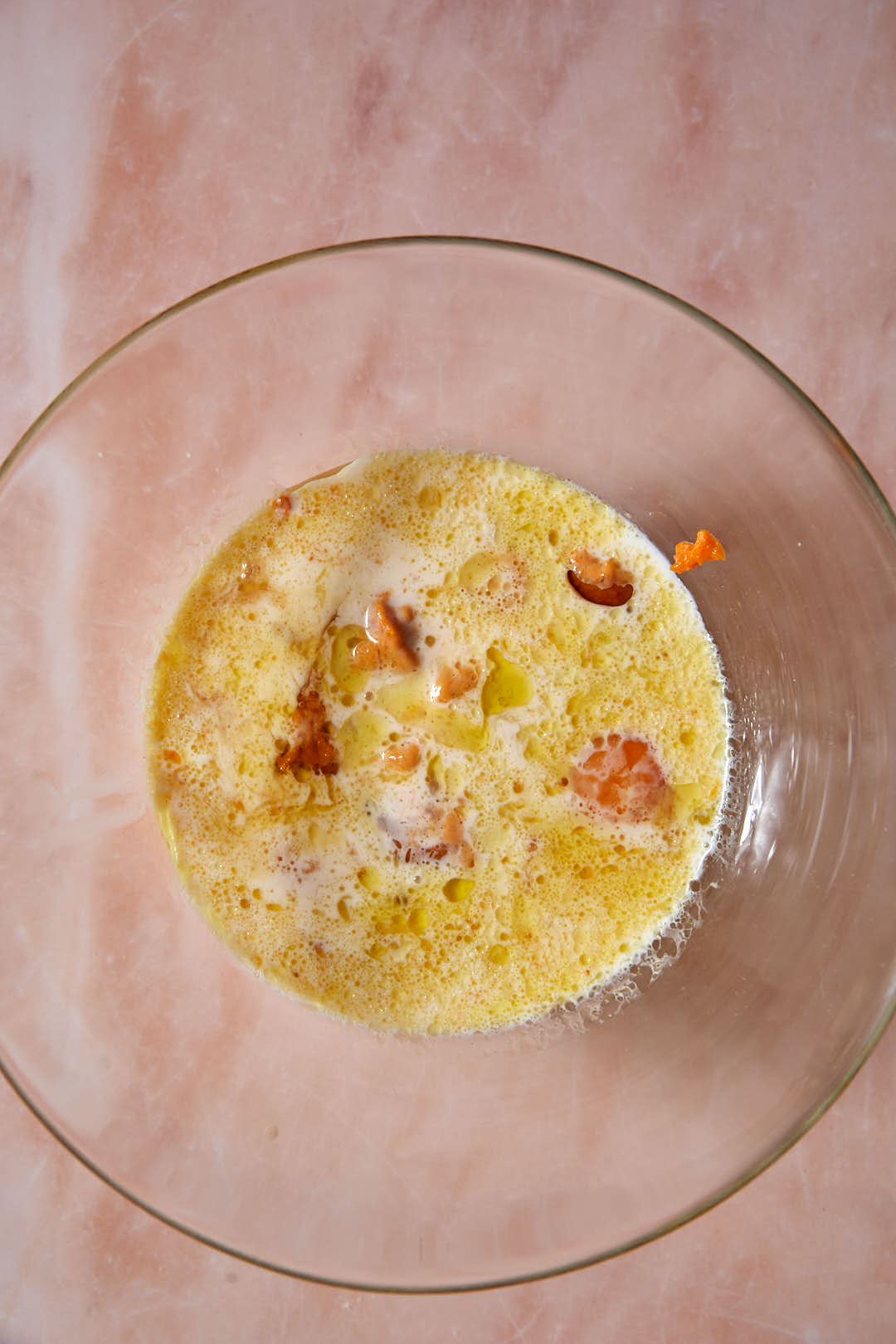 Buttermilk, oil, eggs, and canned pumpkin in a glass bowl.