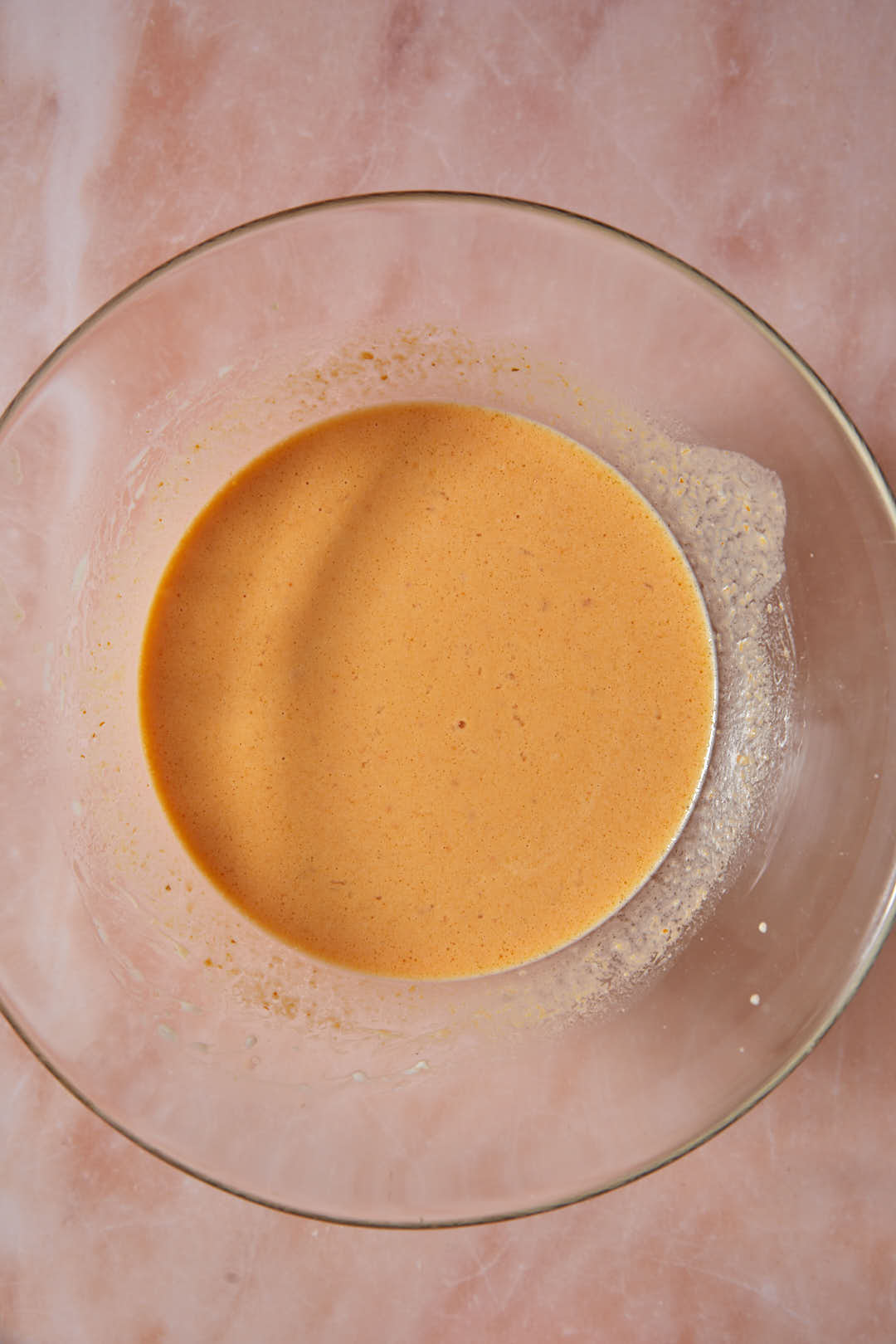 Whisked pumpkin puree and wet ingredients in a glass bowl.