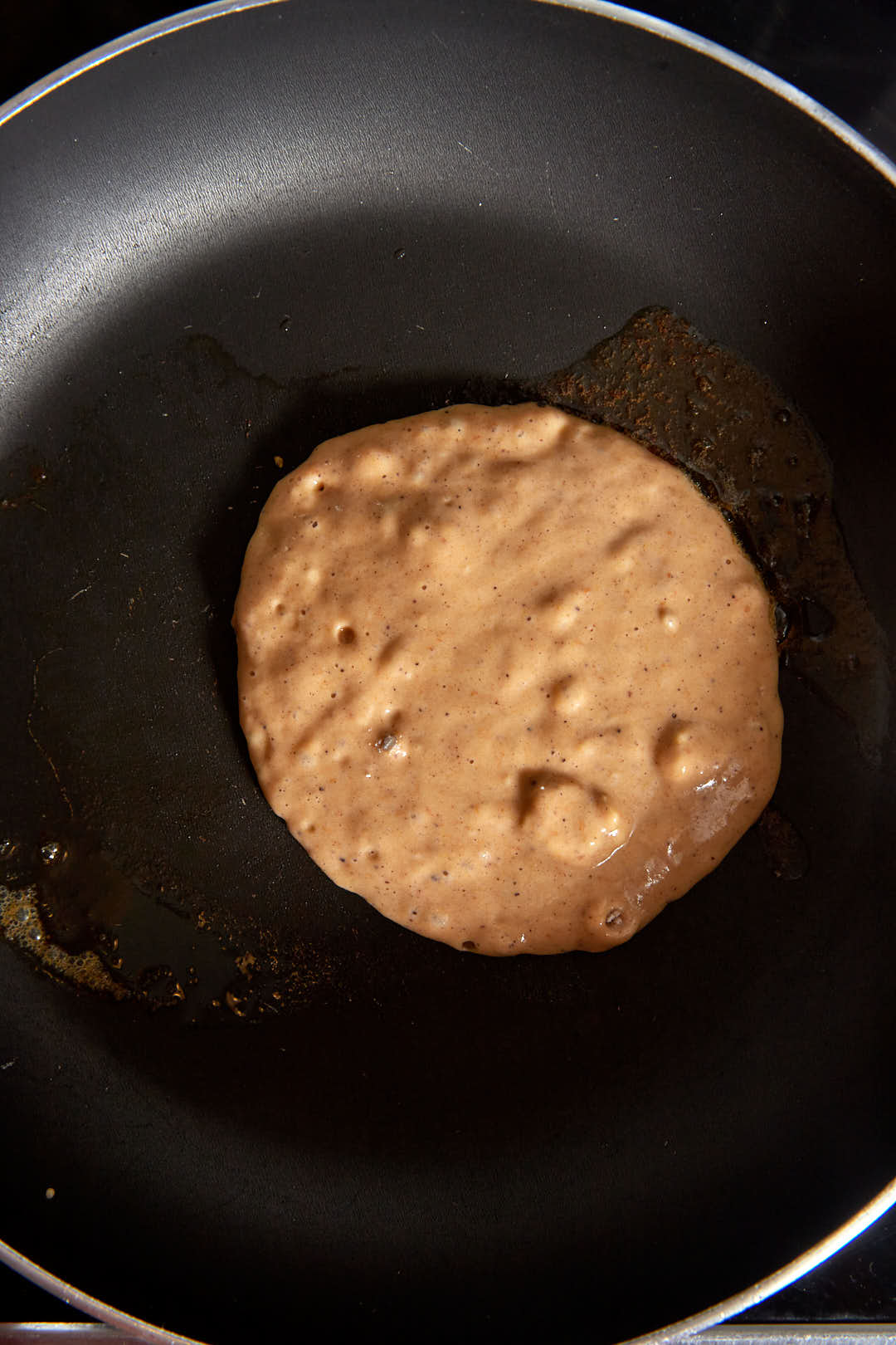1/4 cup of pumpkin pancake batter in a skillet while cooking.