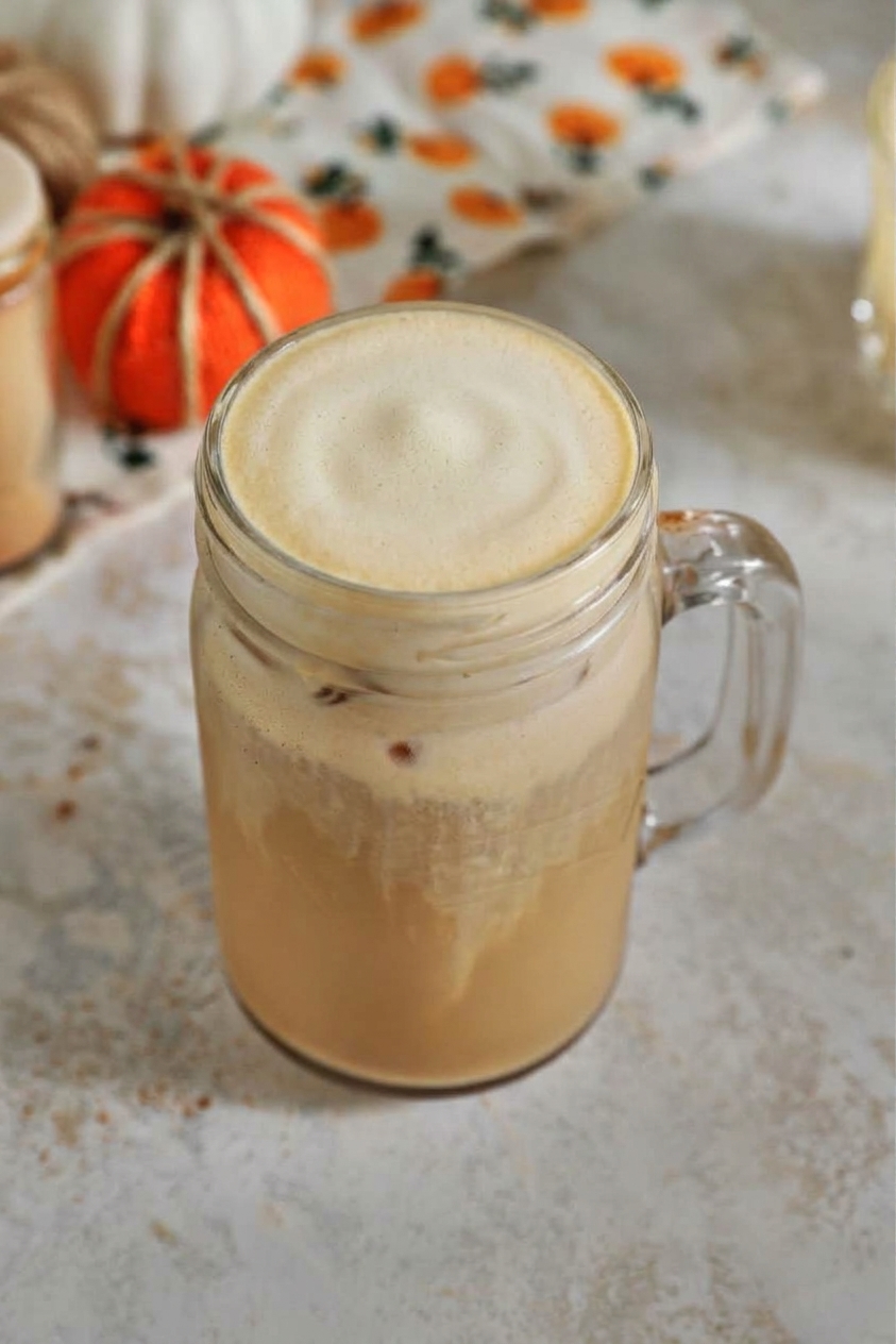 pumpkin cold foam on top of an iced latte in a glass mason jar.