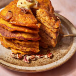 stack of pumpkin pancakes with a bite cut out of the stack.