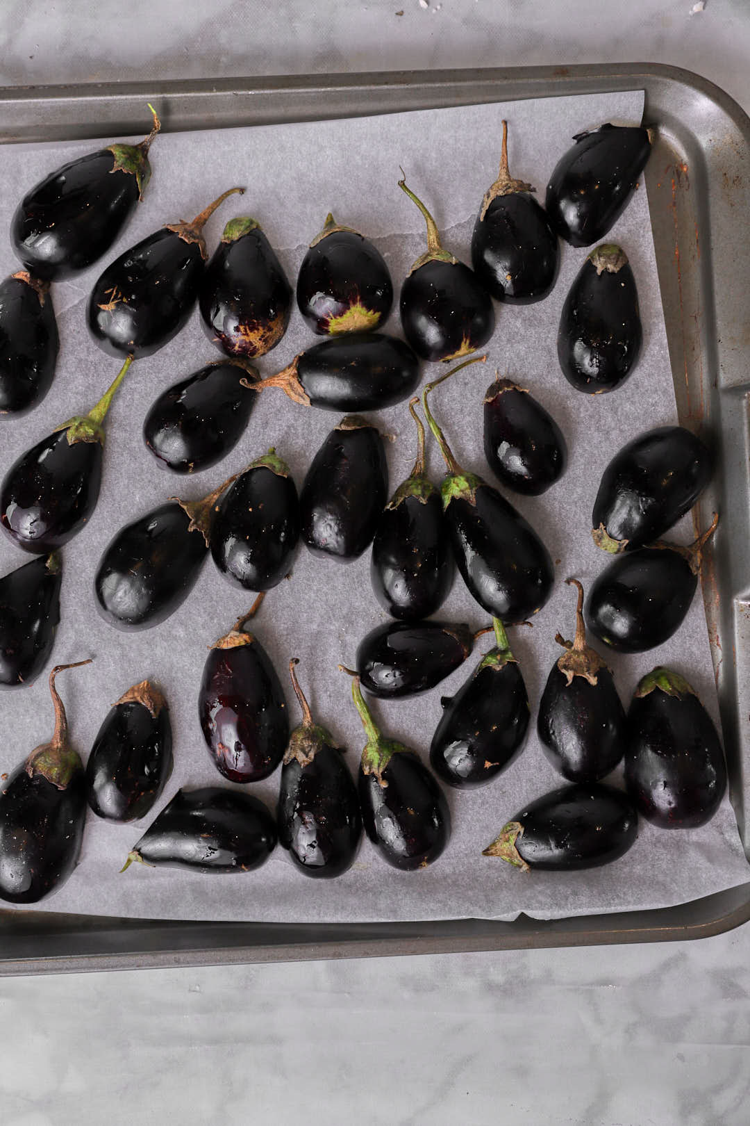 baby eggplants cut side down on baking sheet.