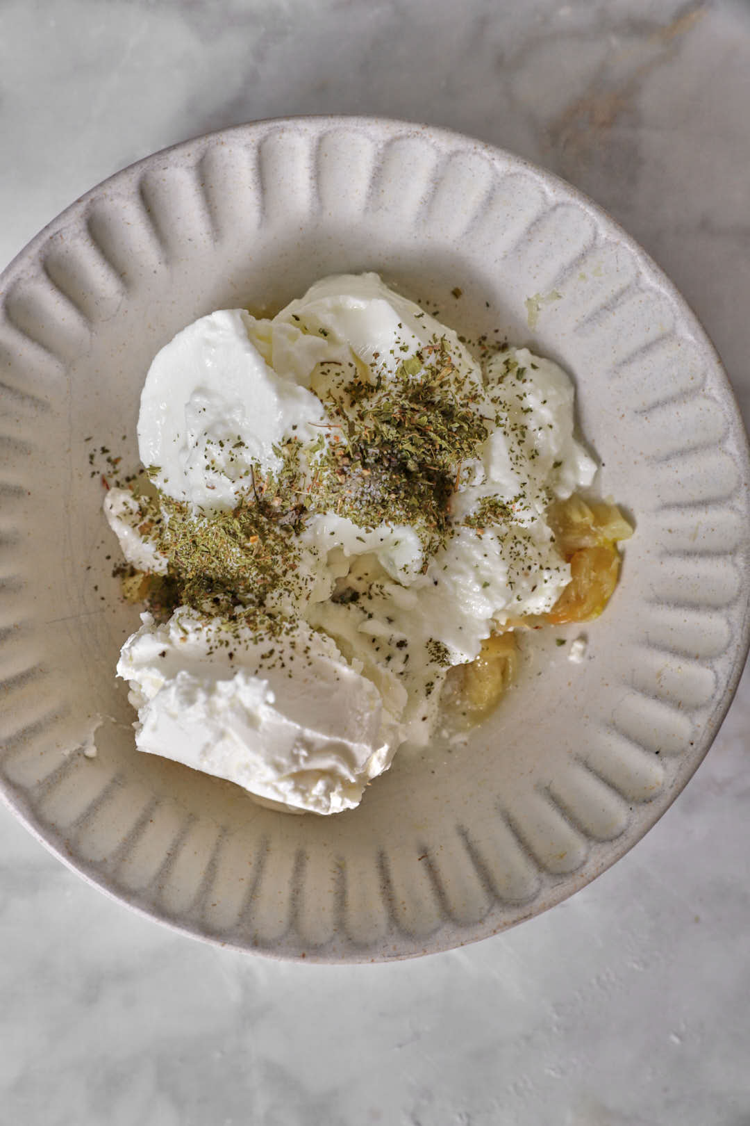 Yogurt and labneh added to a bowl with garlic cloves.