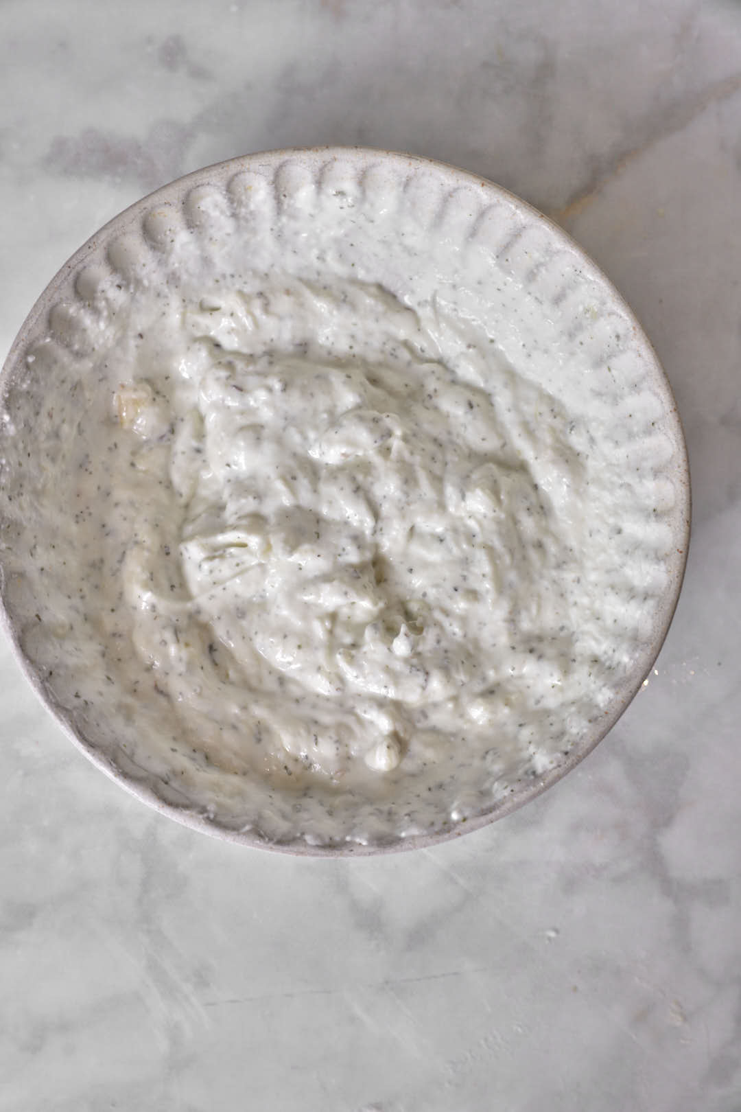 Garlic yogurt sauce in a beige bowl.