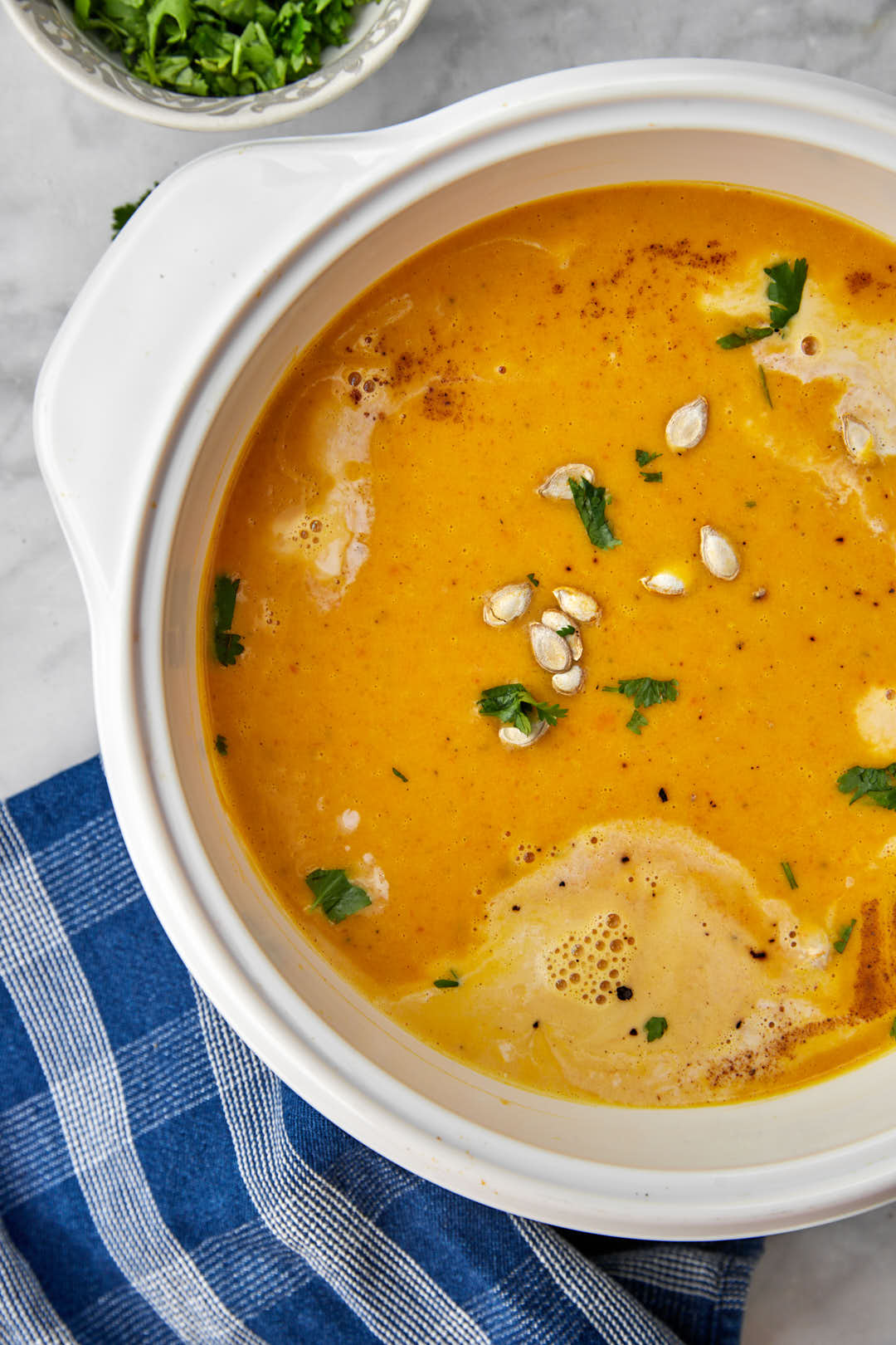 zoomed in photo of roasted carrot and butternut squash soup on a blue kitchen towel.