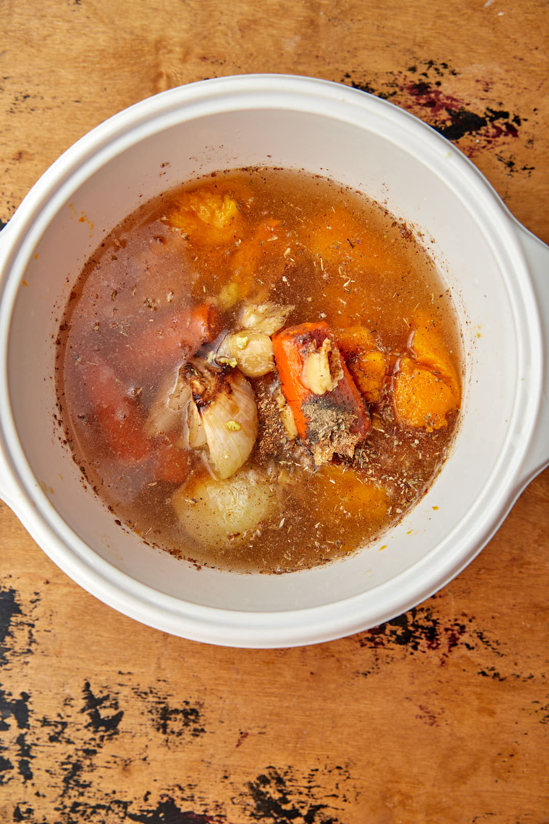 Broth added to butternut squash in white saucepan.