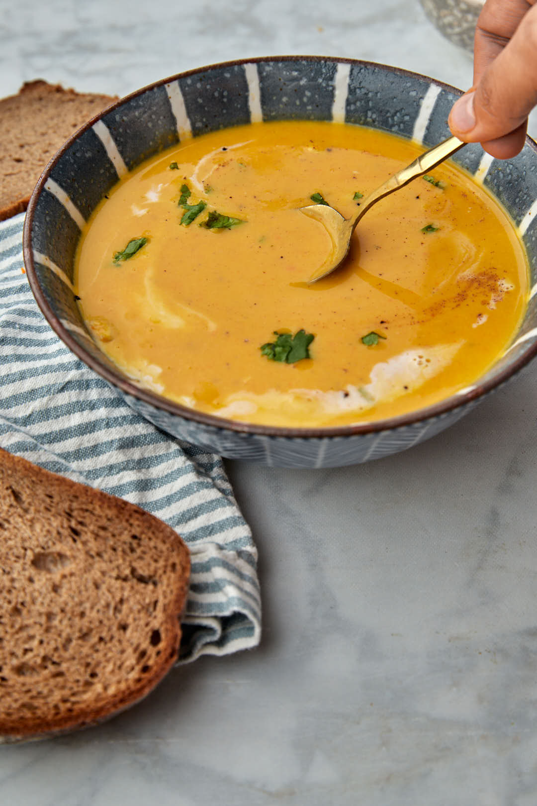 Spoon of butternut squash soup being taken out of a bowl of soup.