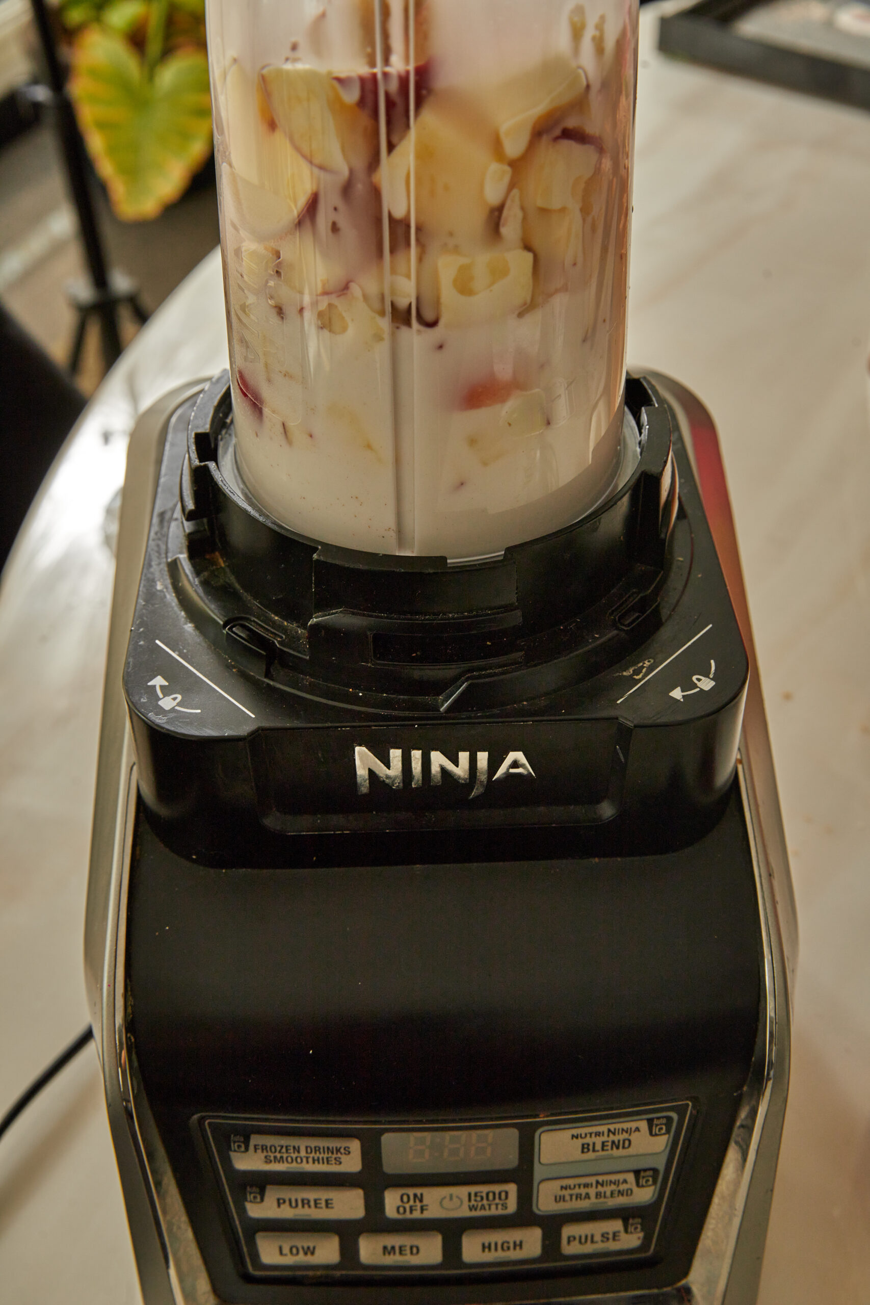 apples and coconut milk being blended in a ninja blender to make apple popsicles.