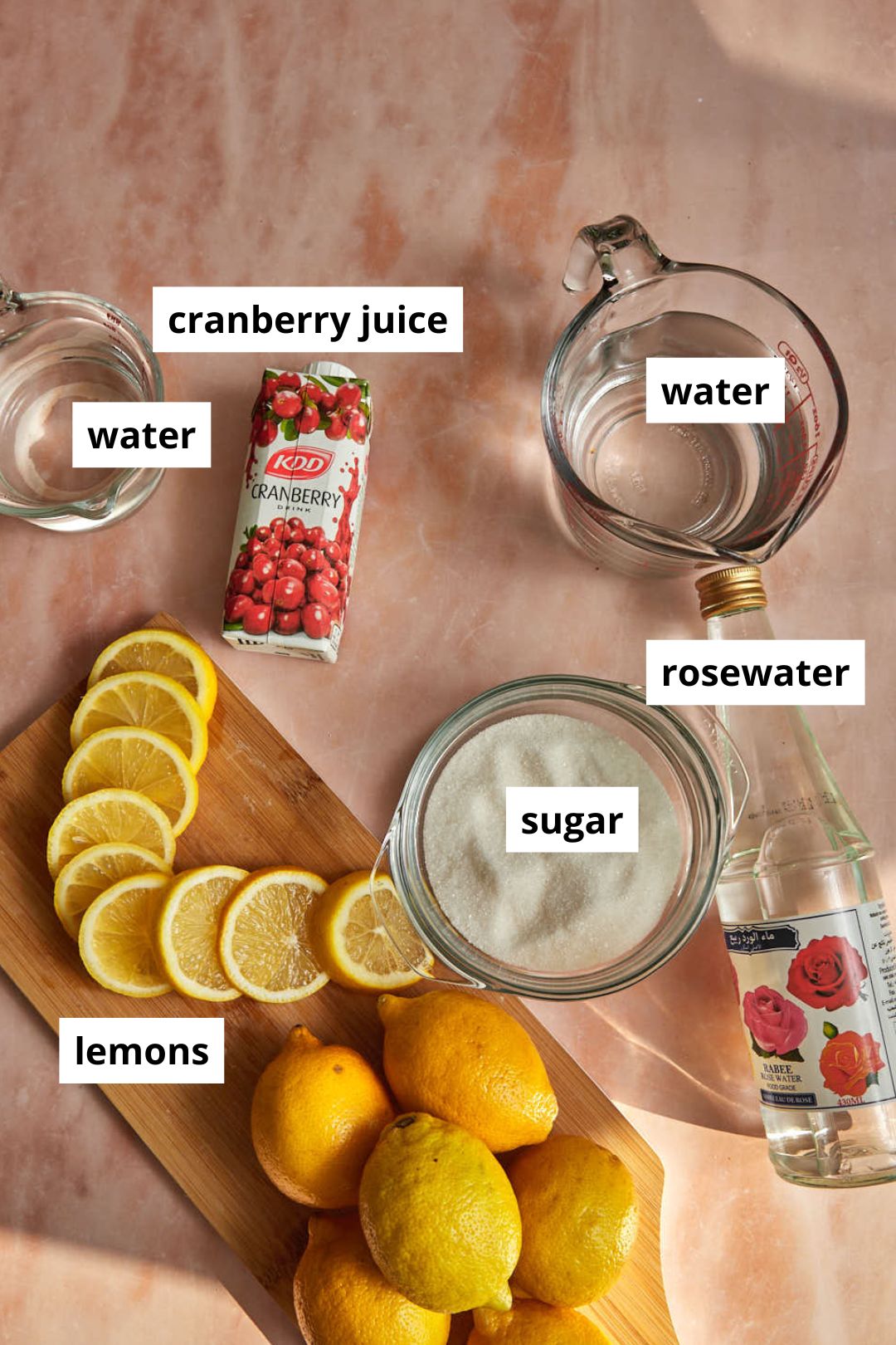 ingredients needed to make rose lemonade on a pink background.