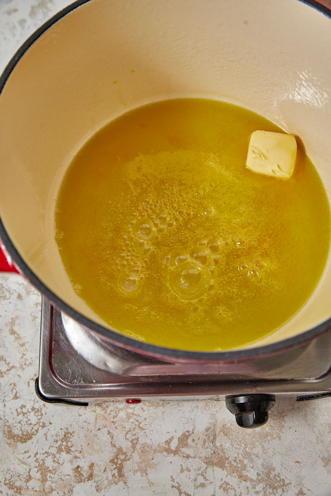 olive oil and butter heating in a large red pot.