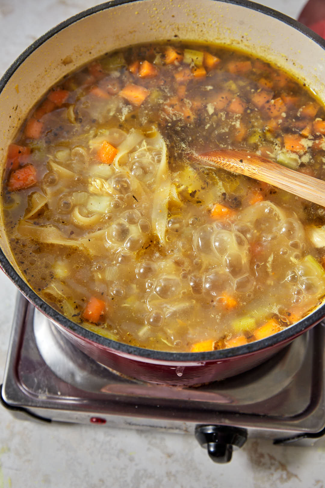 tagliatelle noodles cooking in simmering chicken soup.