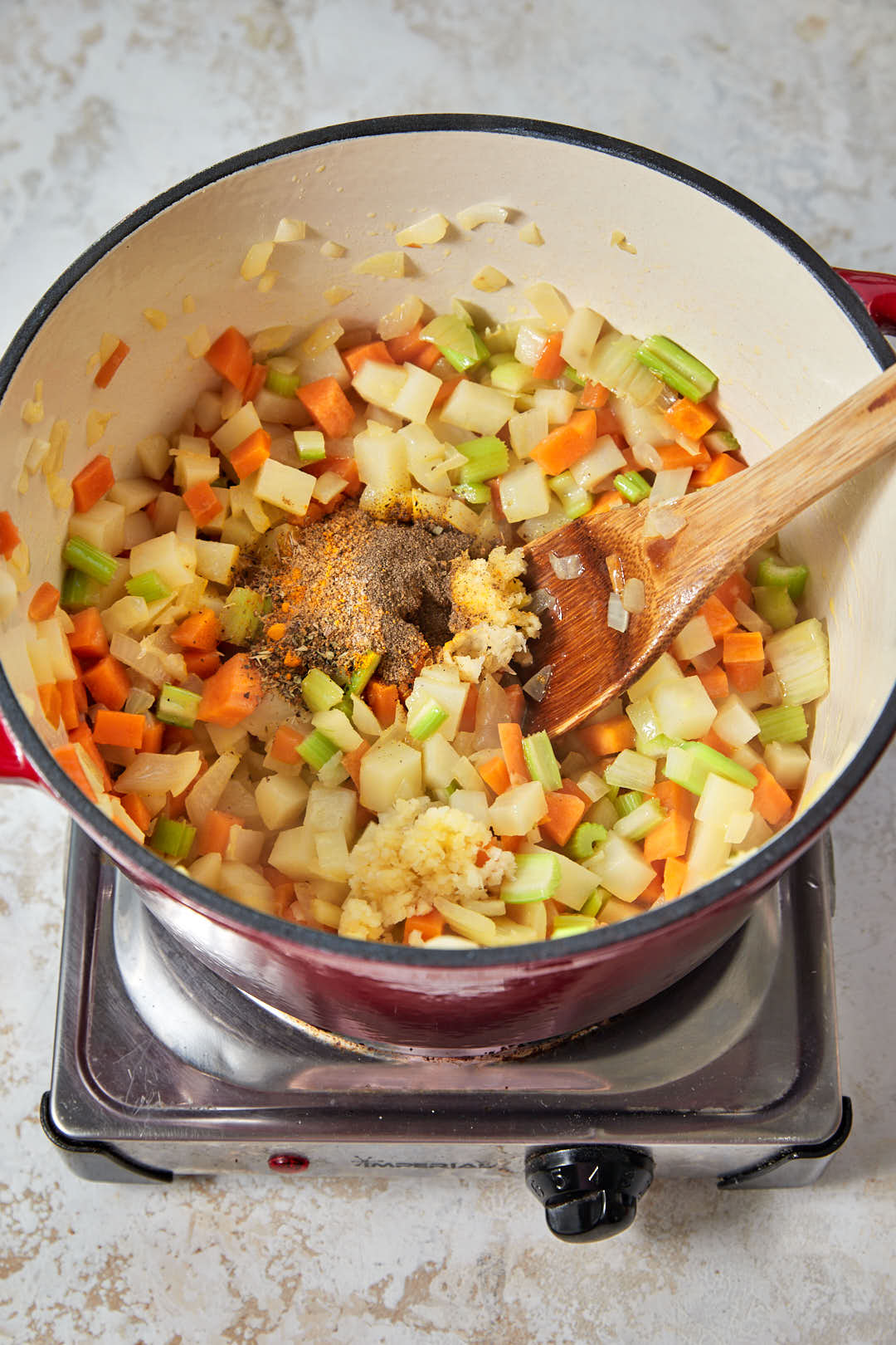 minced garlic, salt and dried spices added on top of sautéed vegetables in a pot.