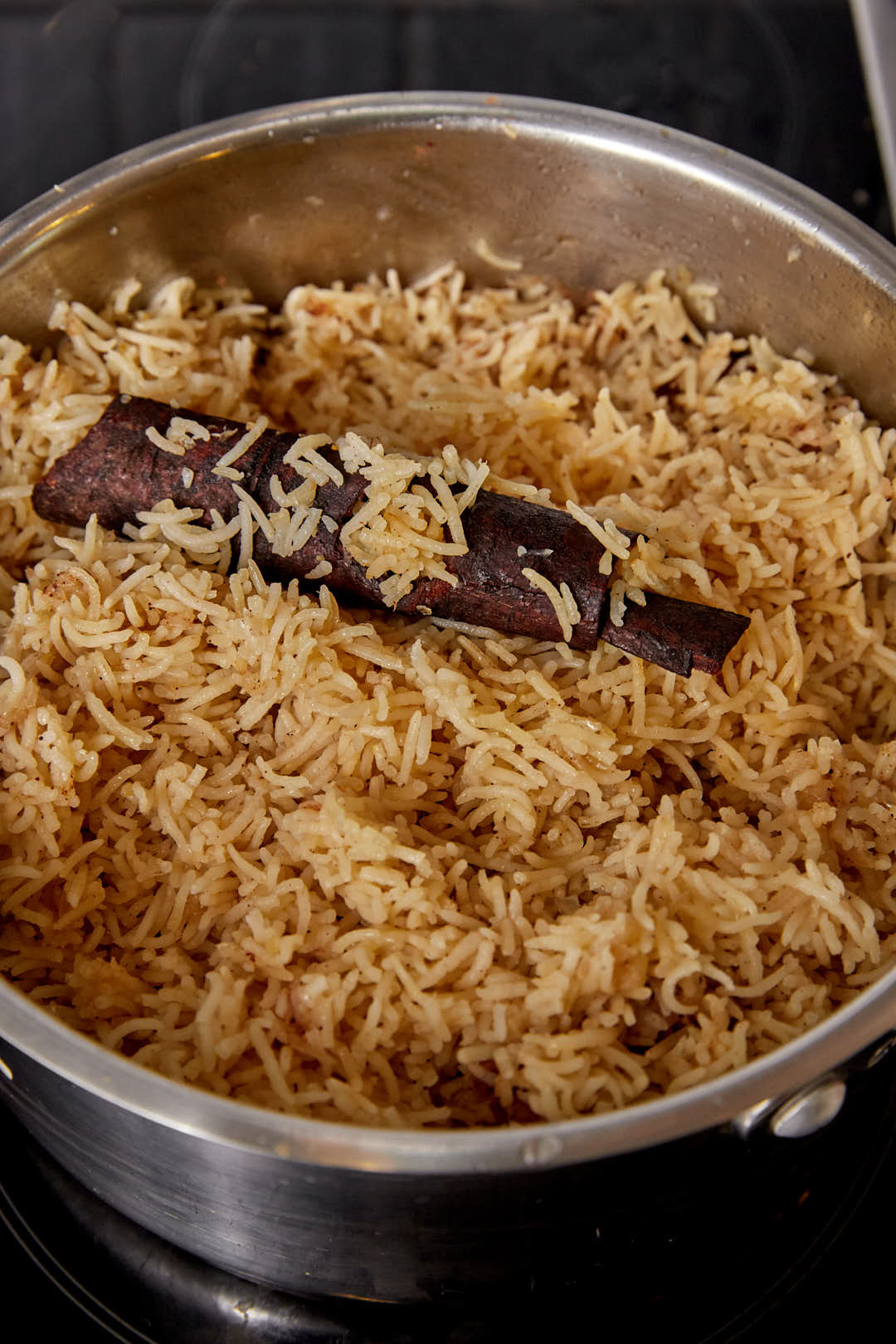 fluffed basmati rice in a large saucepan with a cinnamon stick.