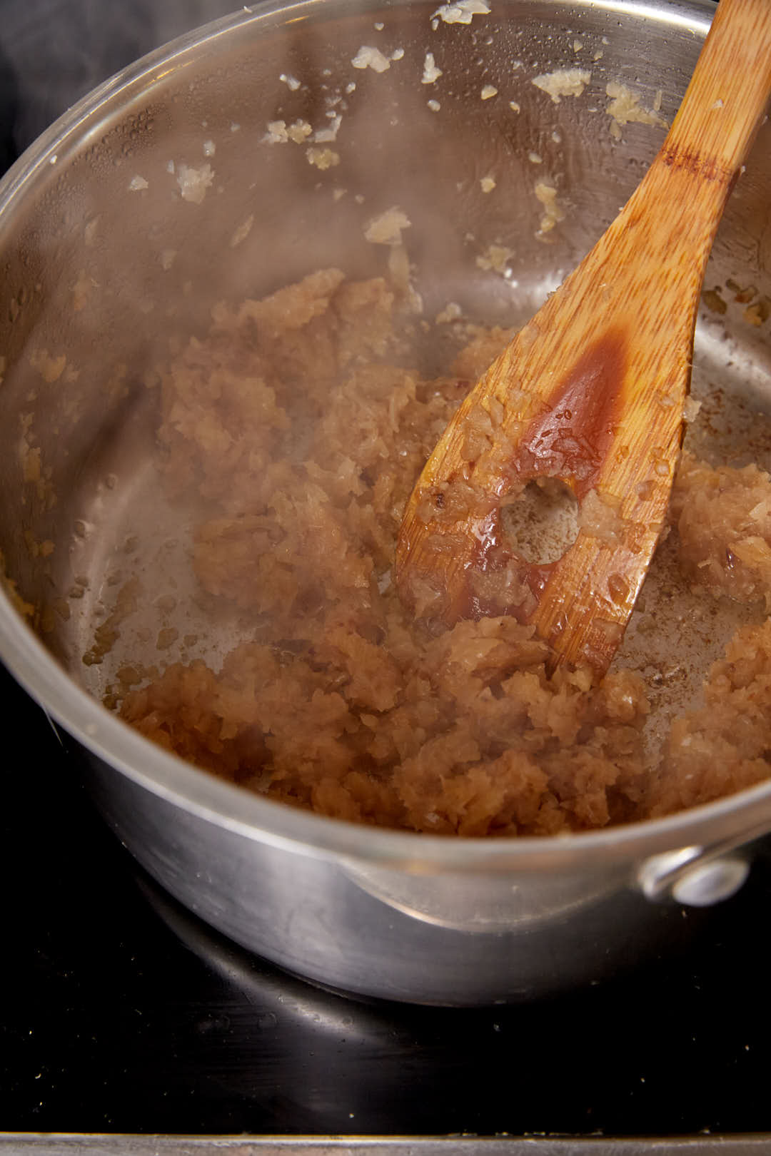 caramelized grated onions in a large pot with a wooden spoon.