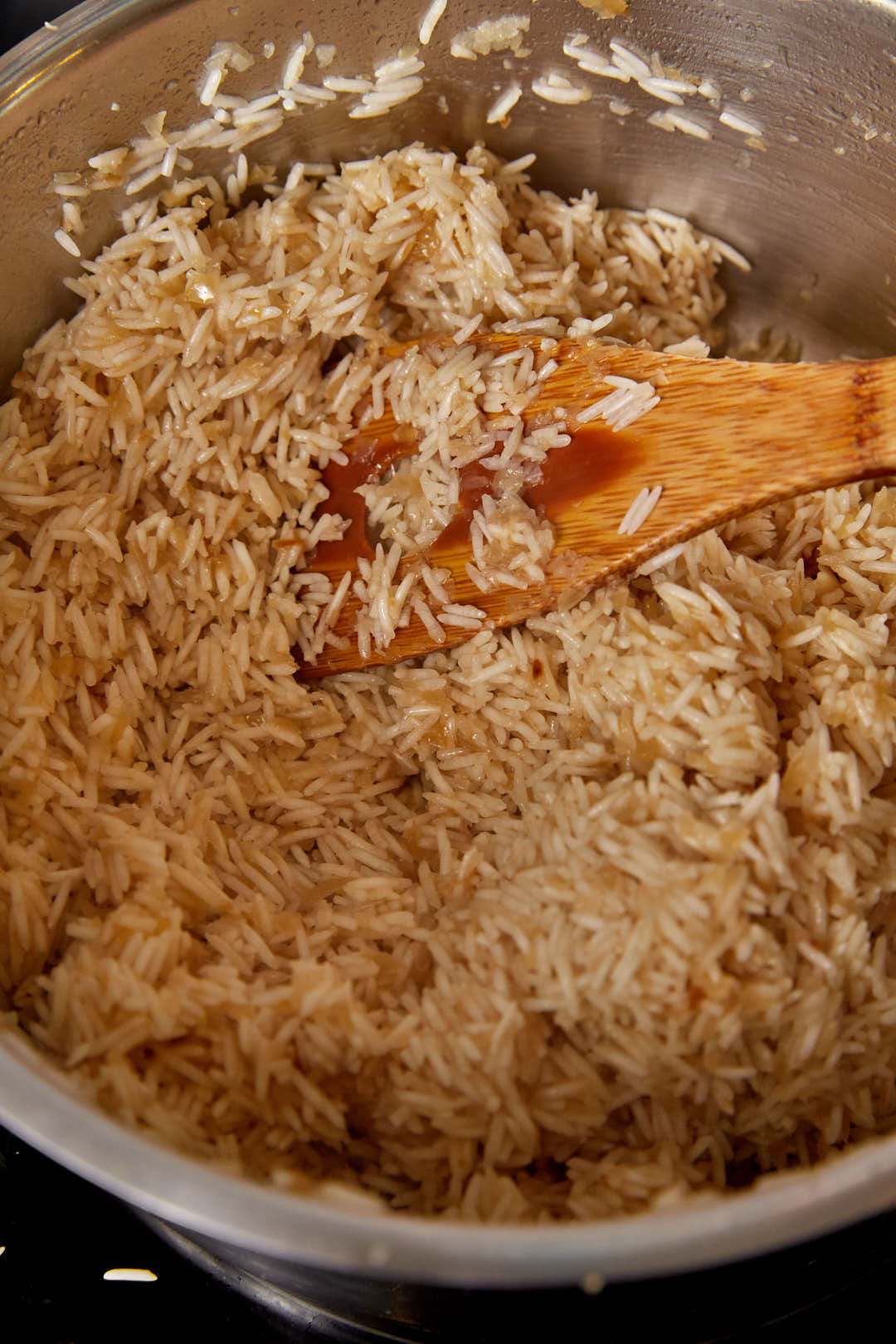basmati rice mixed with caramelized onions before cooking in a large pot.