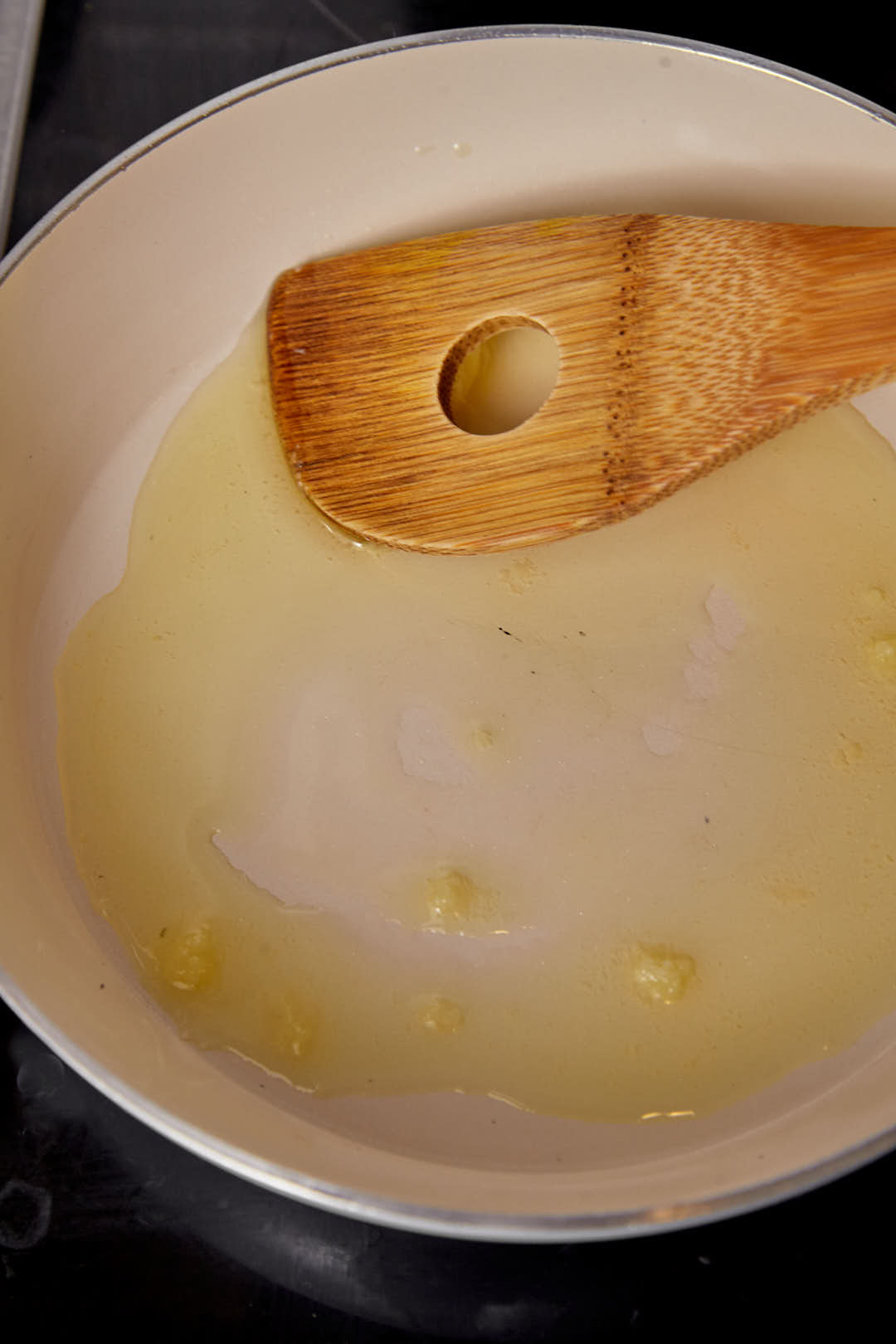 melted ghee in a skillet with a wooden spoon.