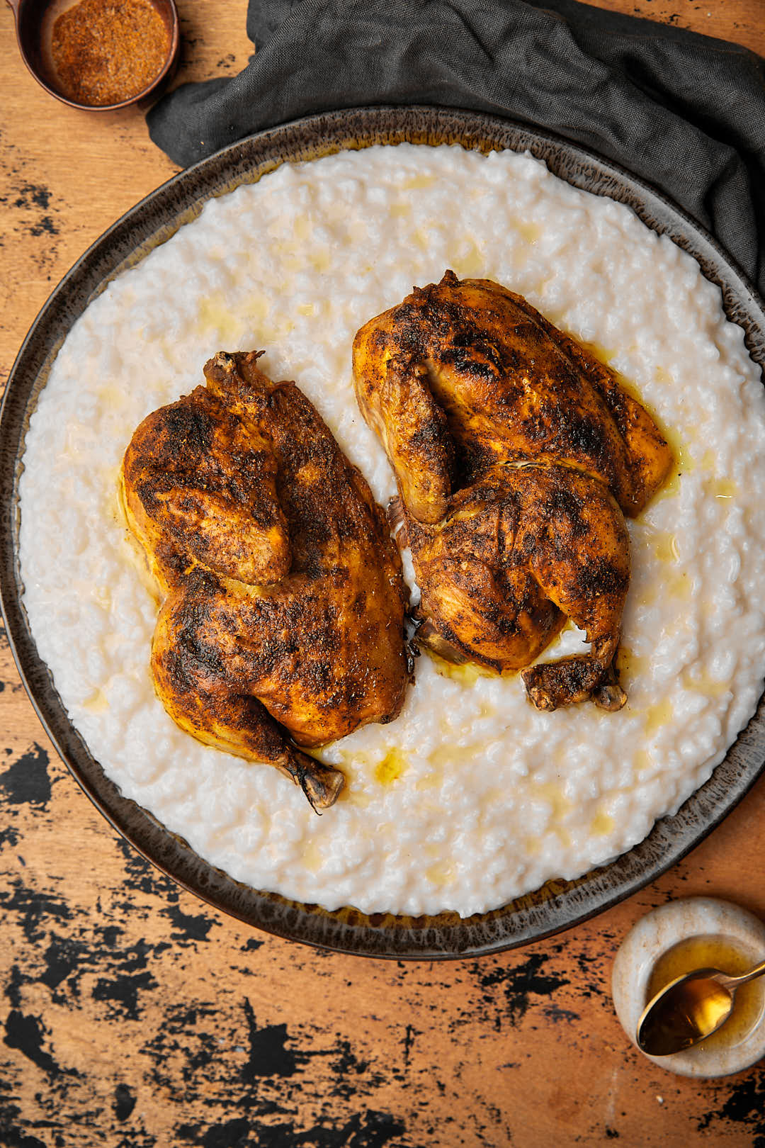 a platter of saleeg with roasted chicken halves on it on a wooden background.