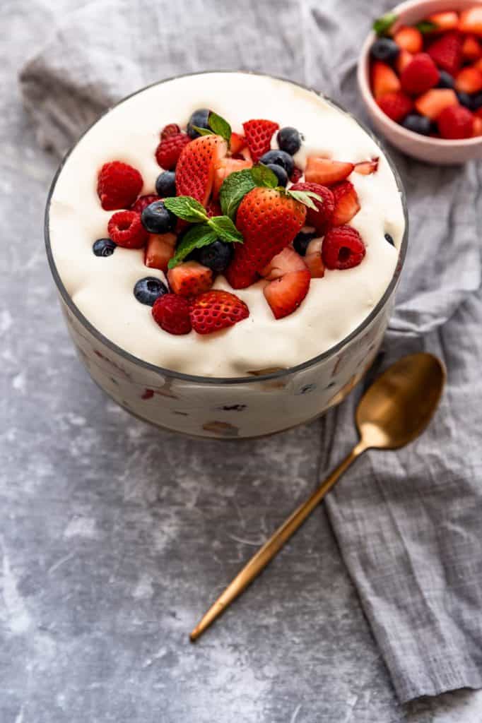 berries and cream trifle with bowl of berries in background