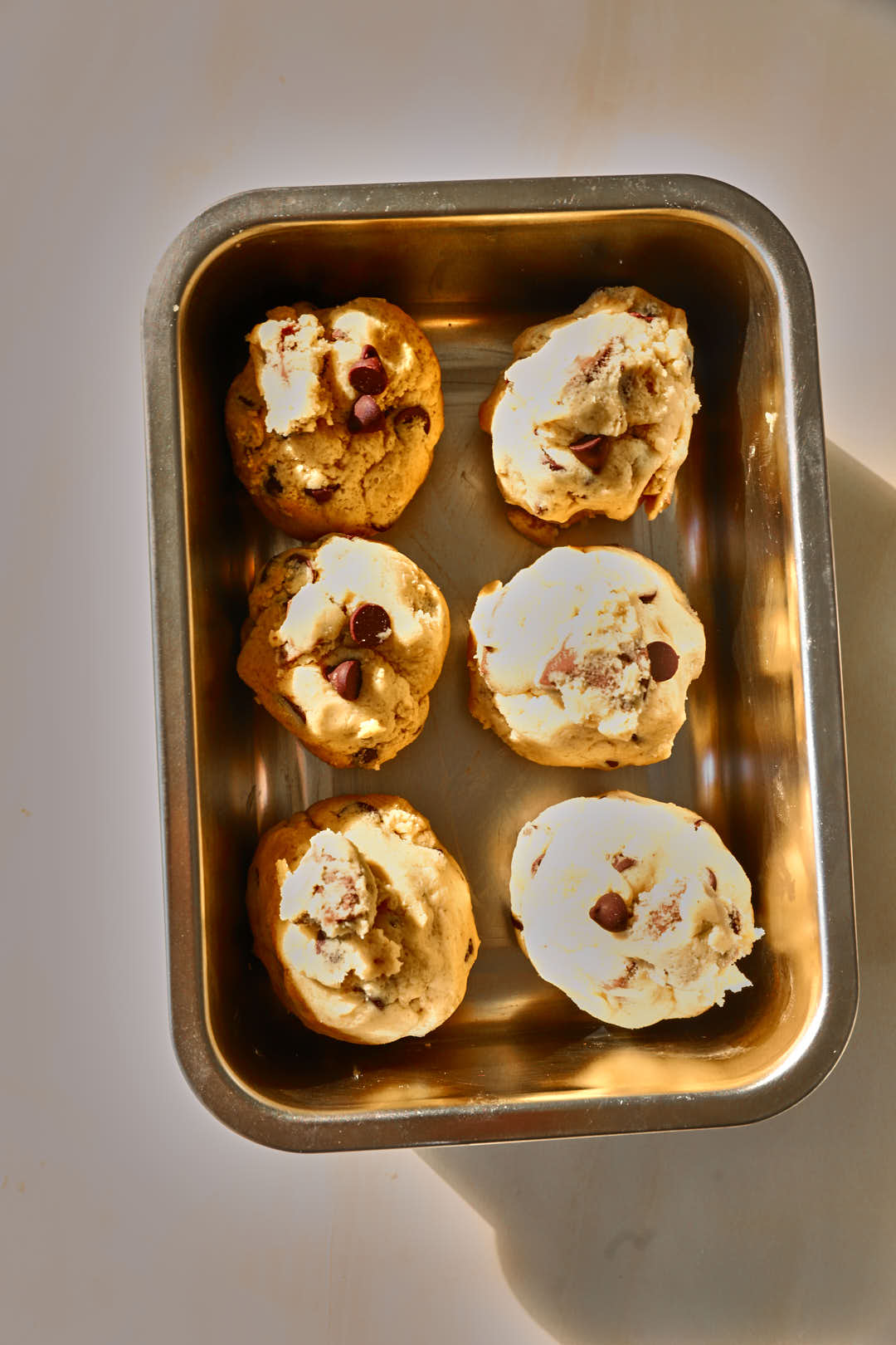 Cookie dough scooped into large balls and placed close to each other on a baking sheet.