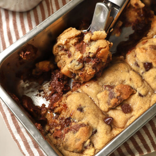 an ice cream scoop with a big scoop of cookies in a pan.