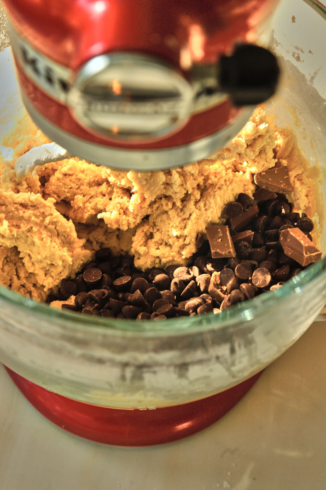 chocolate chips added to cookie dough in glass stand mixer