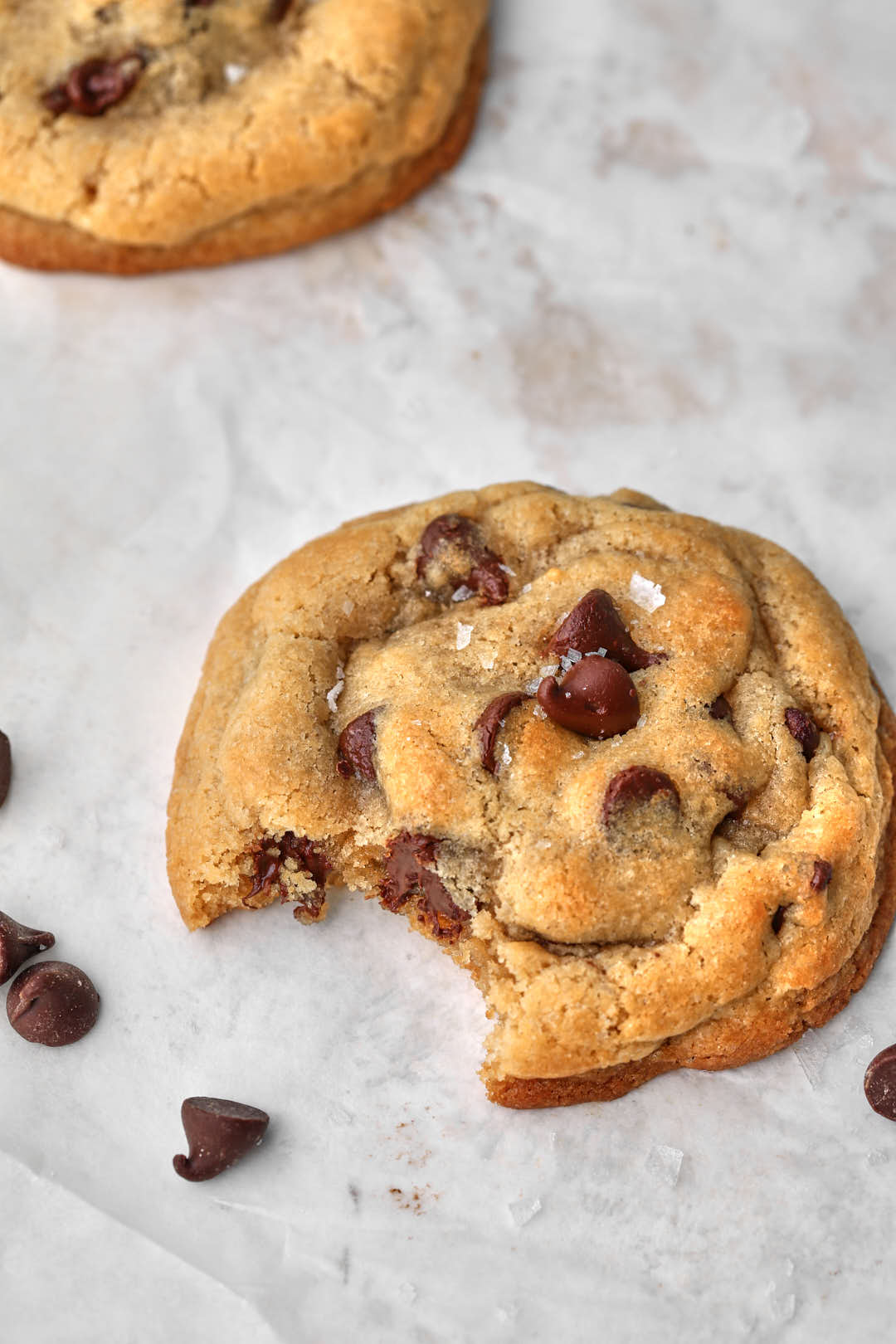 single portion chocolate chip cookie on a white background with a bite taken out.