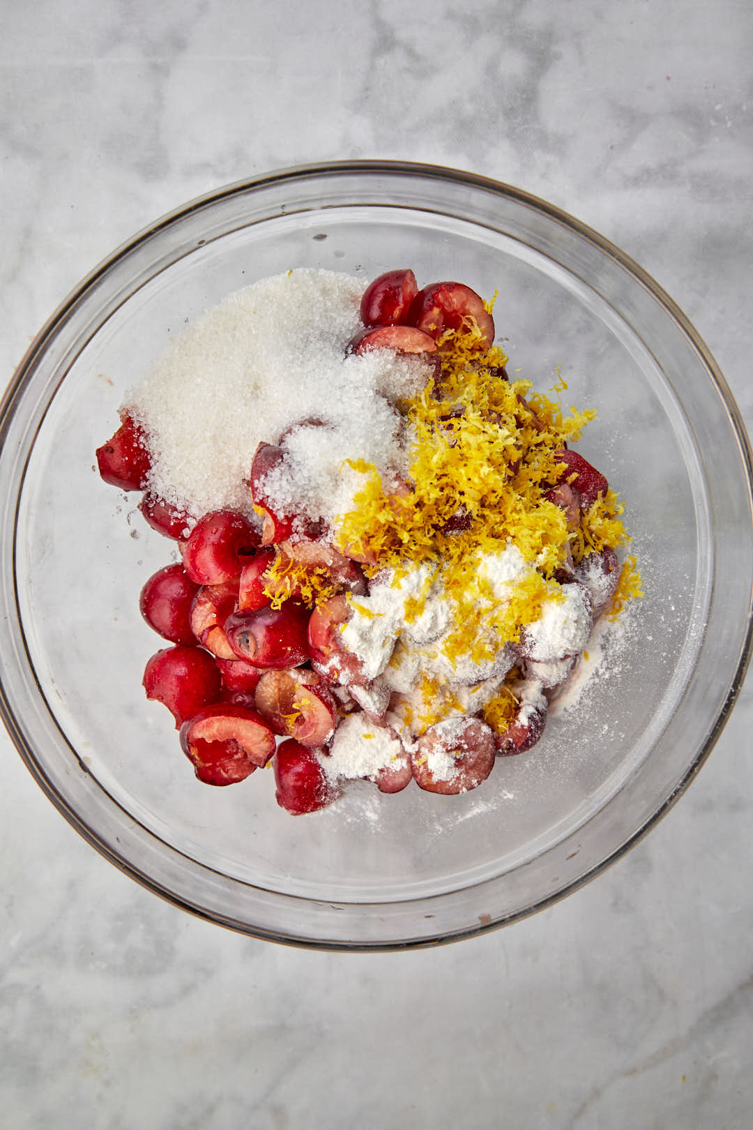 frseh cherries in a bowl with flour, lemon zest and sugar