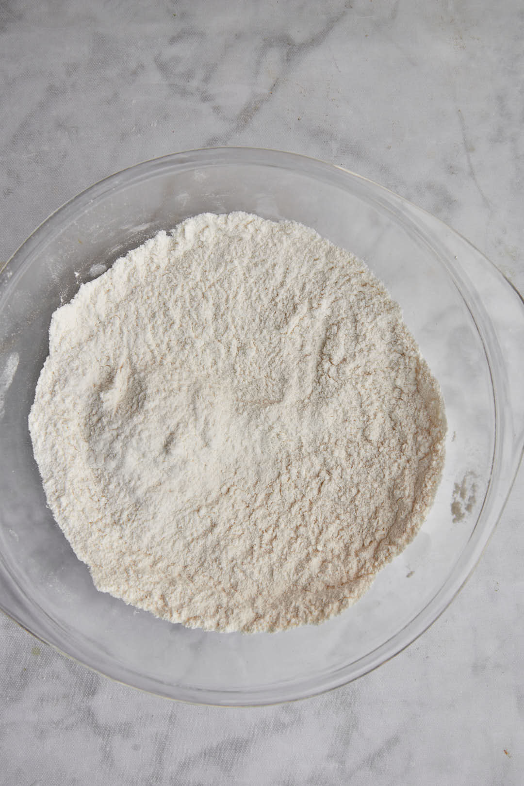 flour, baking powder, sugar and salt mixed together in glass bowl