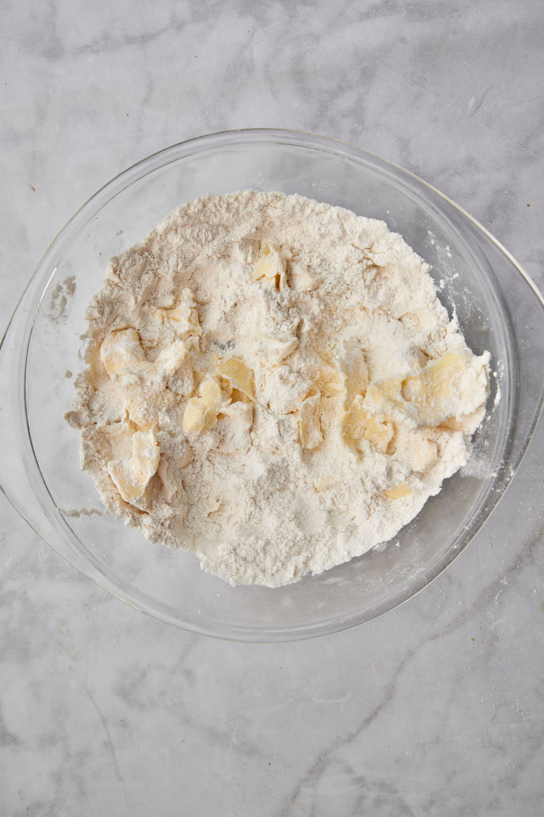 Cold butter pieces added a flour mixture in a bowl