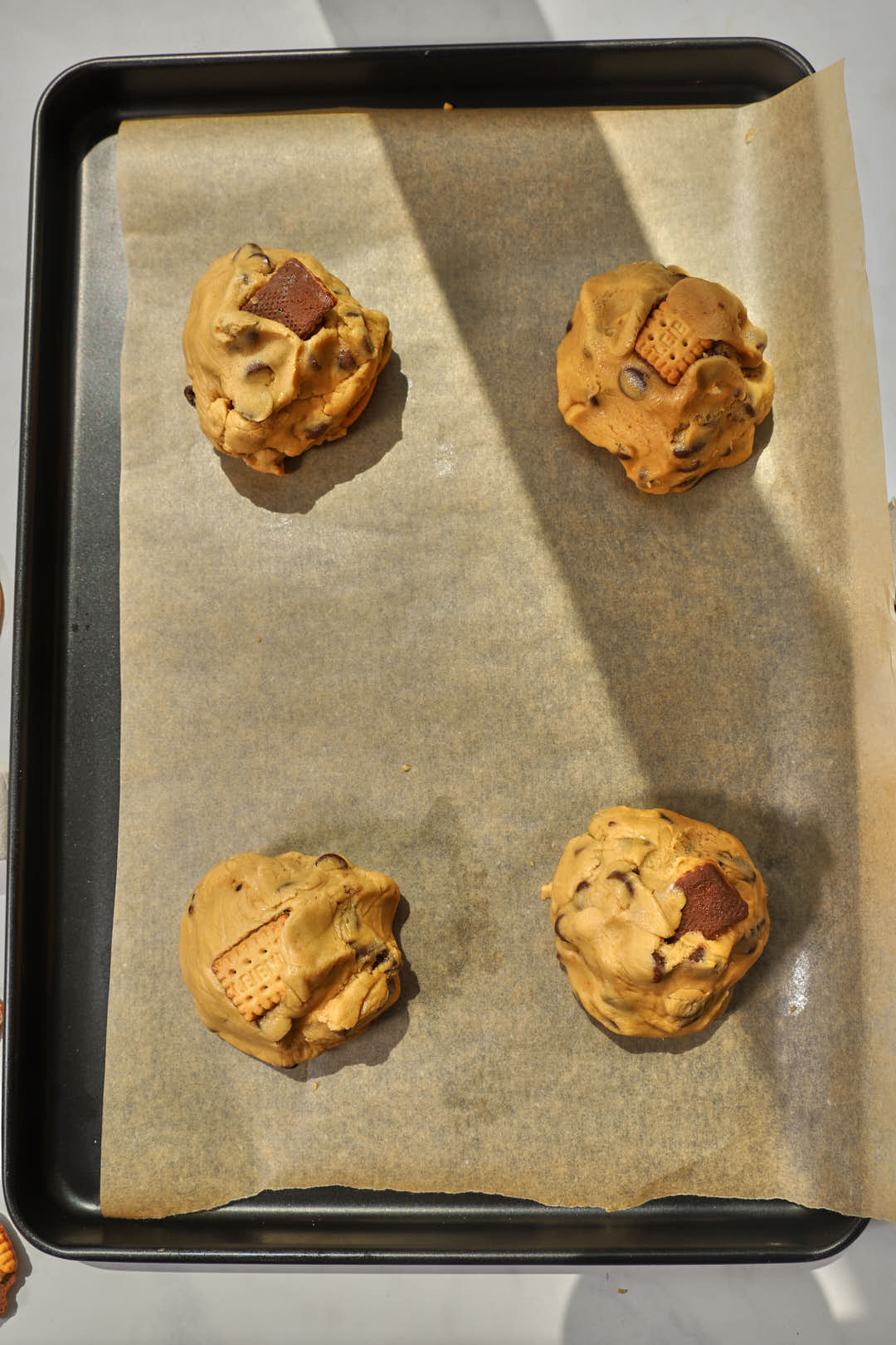 chocolate chip cookie dough wrapped on top of marshmallows chocolate and biscuits to make s'mores cookies.